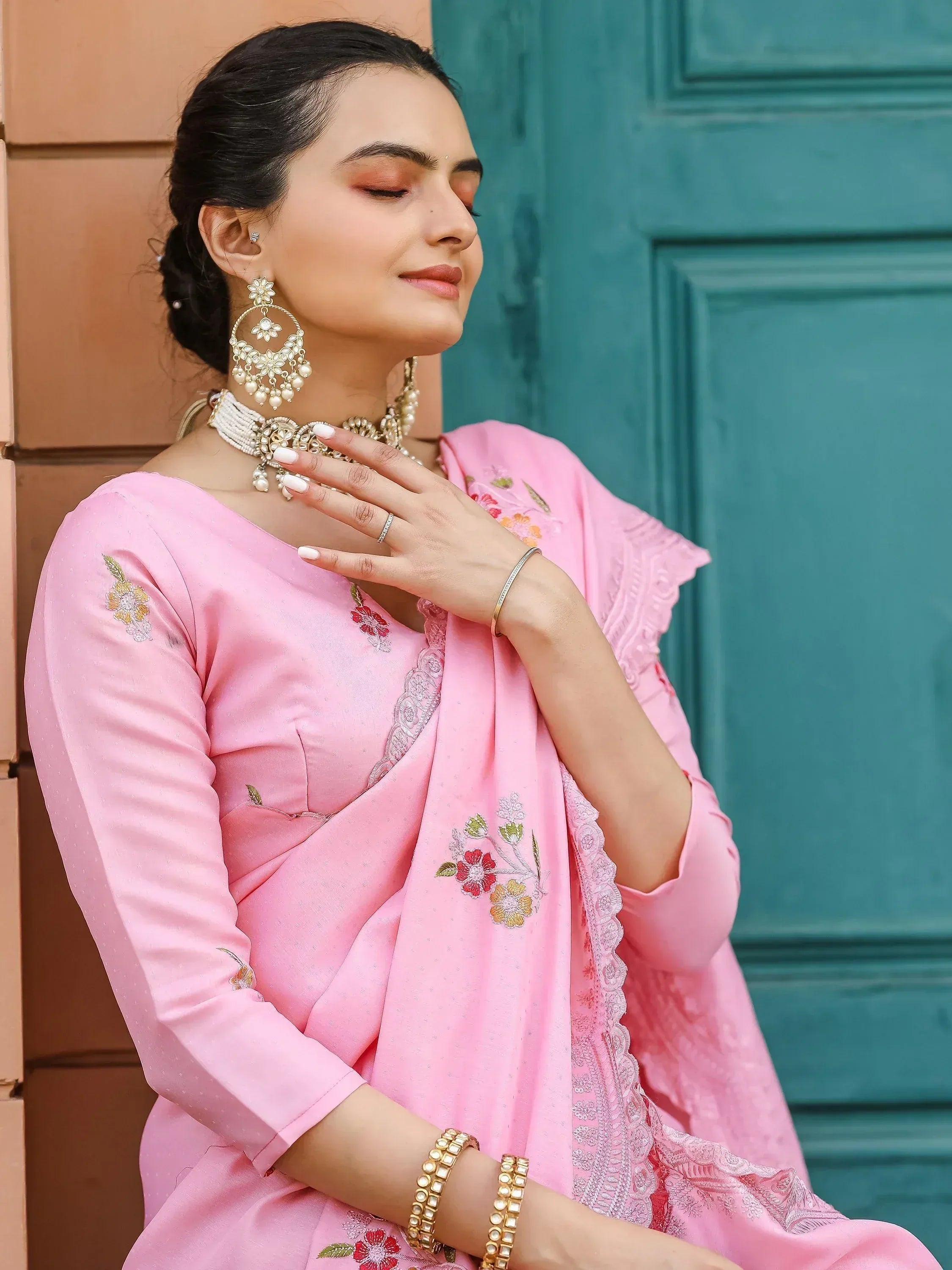 Pink embroidered salwar kameez with floral details and traditional jewelry, perfect for ethnic occasions.