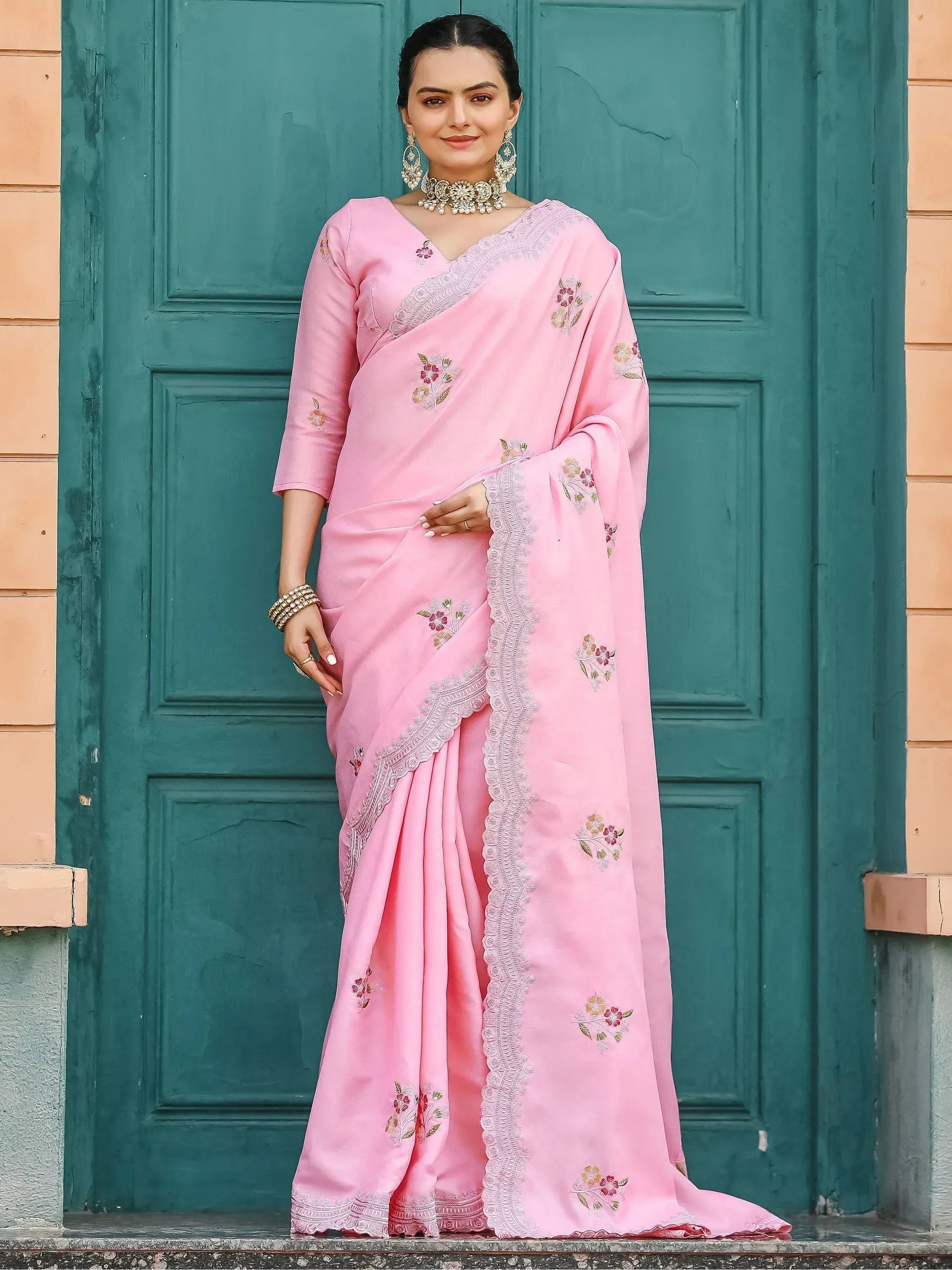 Pink embroidered saree with floral motifs and lace border, styled with traditional jewelry for ethnic wear