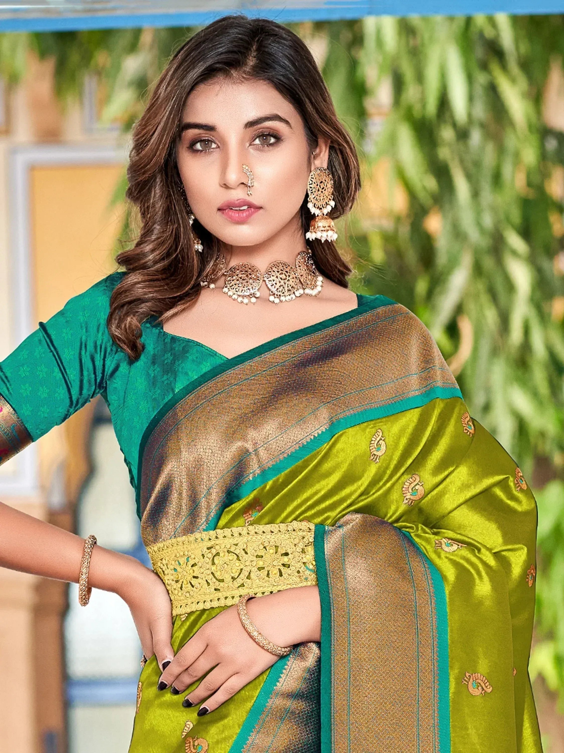 Green and gold embroidered saree with peacock motifs, paired with matching blouse and traditional jewelry