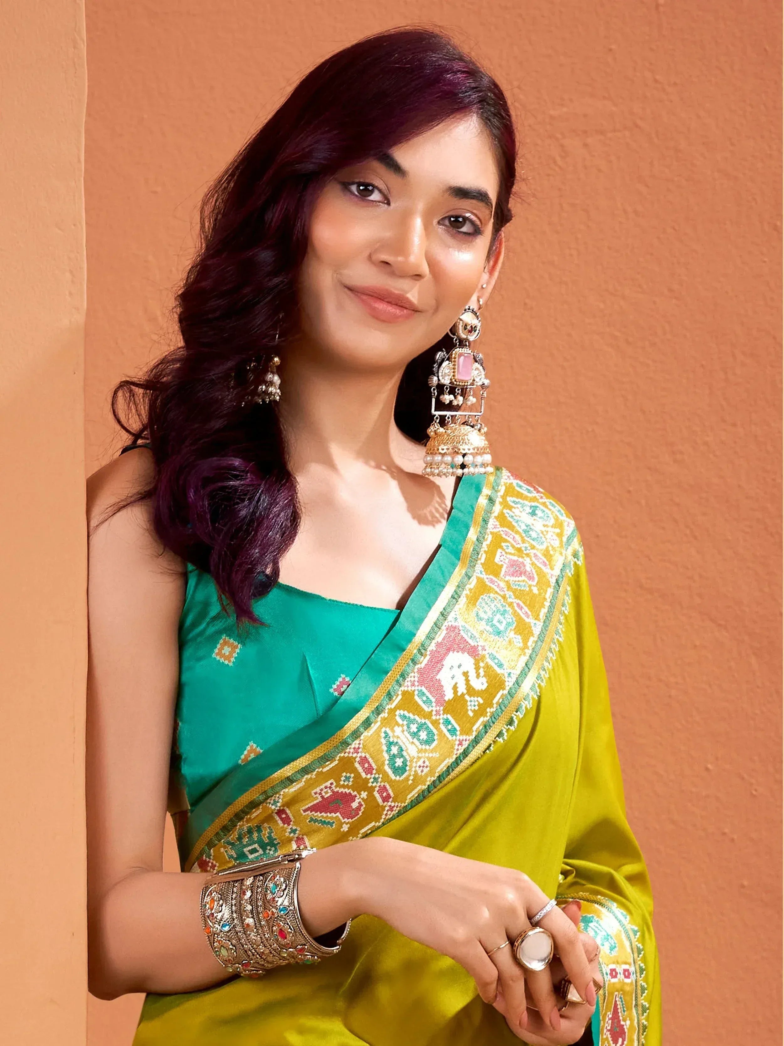 Woman in vibrant green and yellow saree with embroidered border, traditional Indian ethnic wear