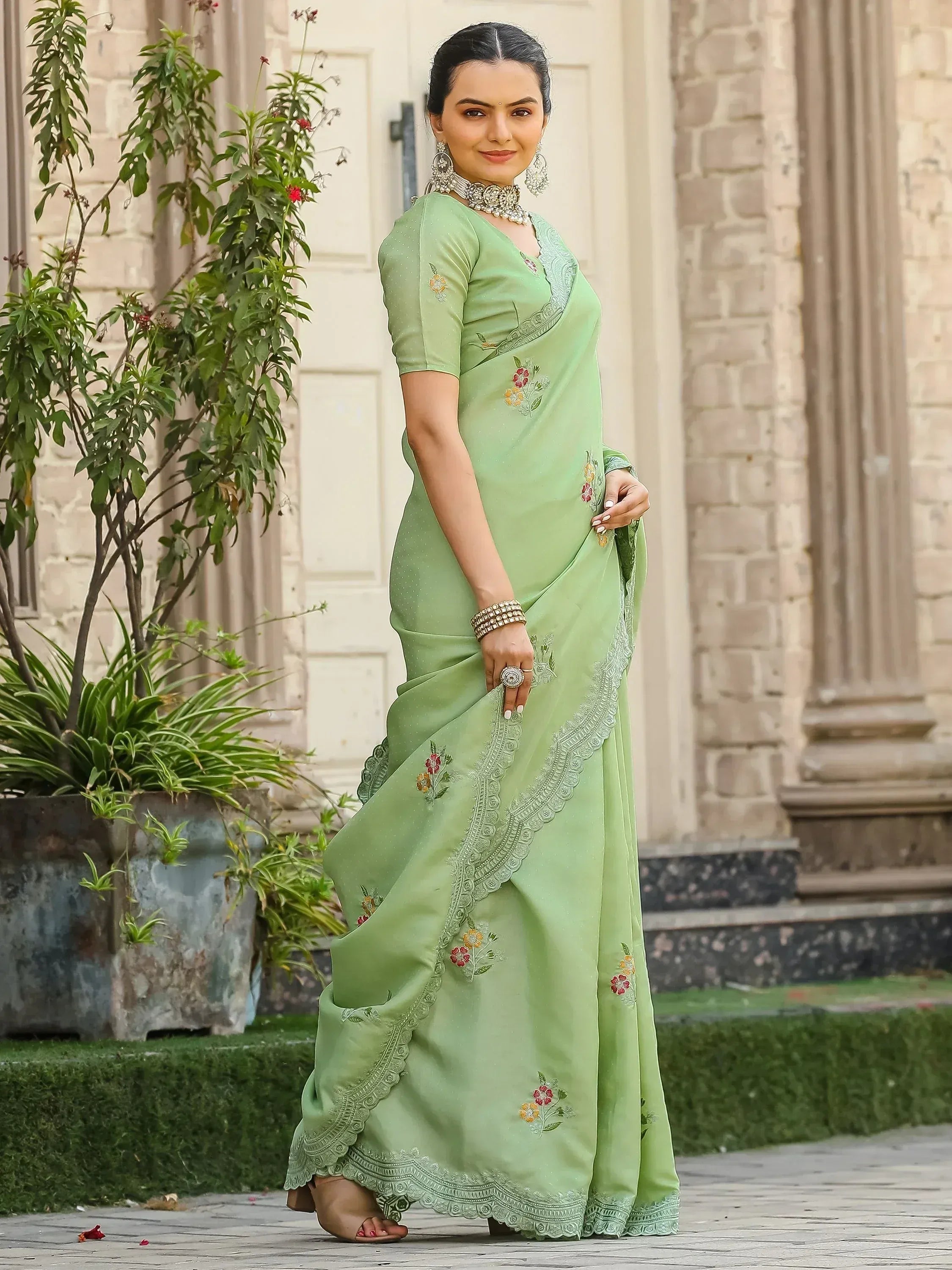 Light green embroidered saree with floral motifs and lace border, styled with traditional jewelry for ethnic wear.
