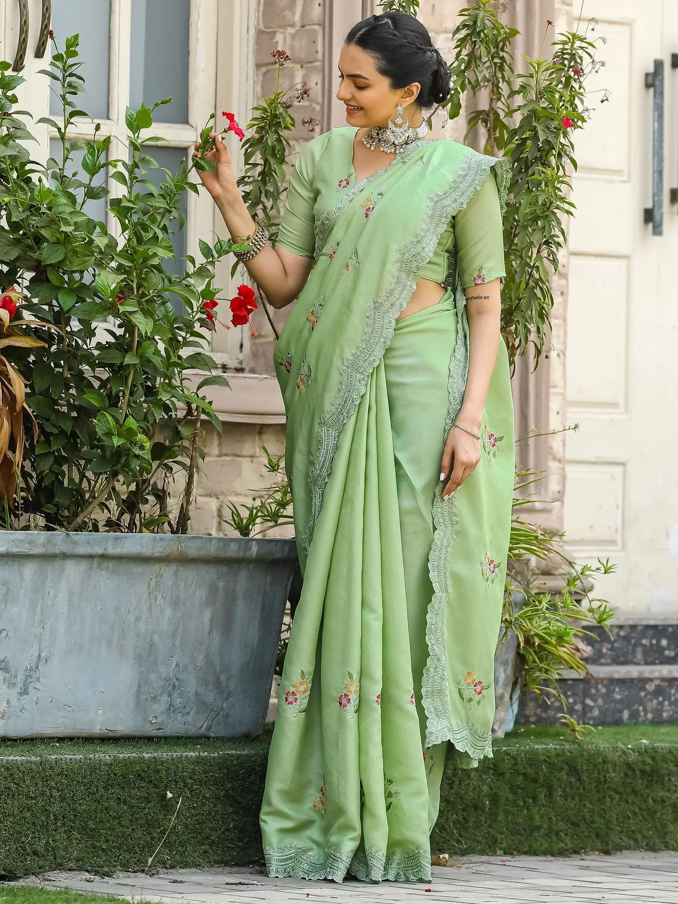 Mint green embroidered saree with floral details and lace border, styled with traditional jewelry for ethnic wear.