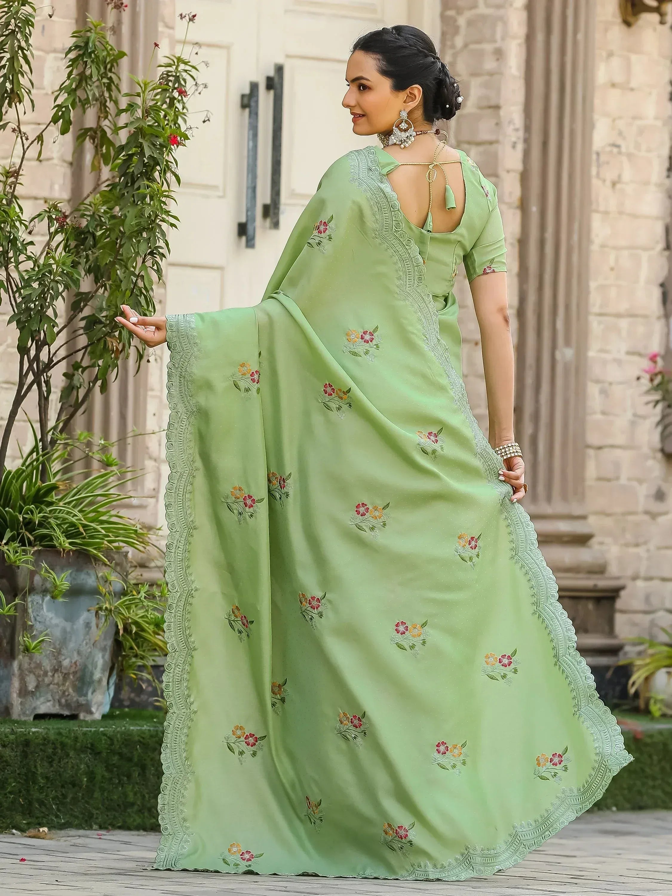 Light green embroidered saree with floral motifs and scalloped border, styled with statement jewelry for ethnic occasions.