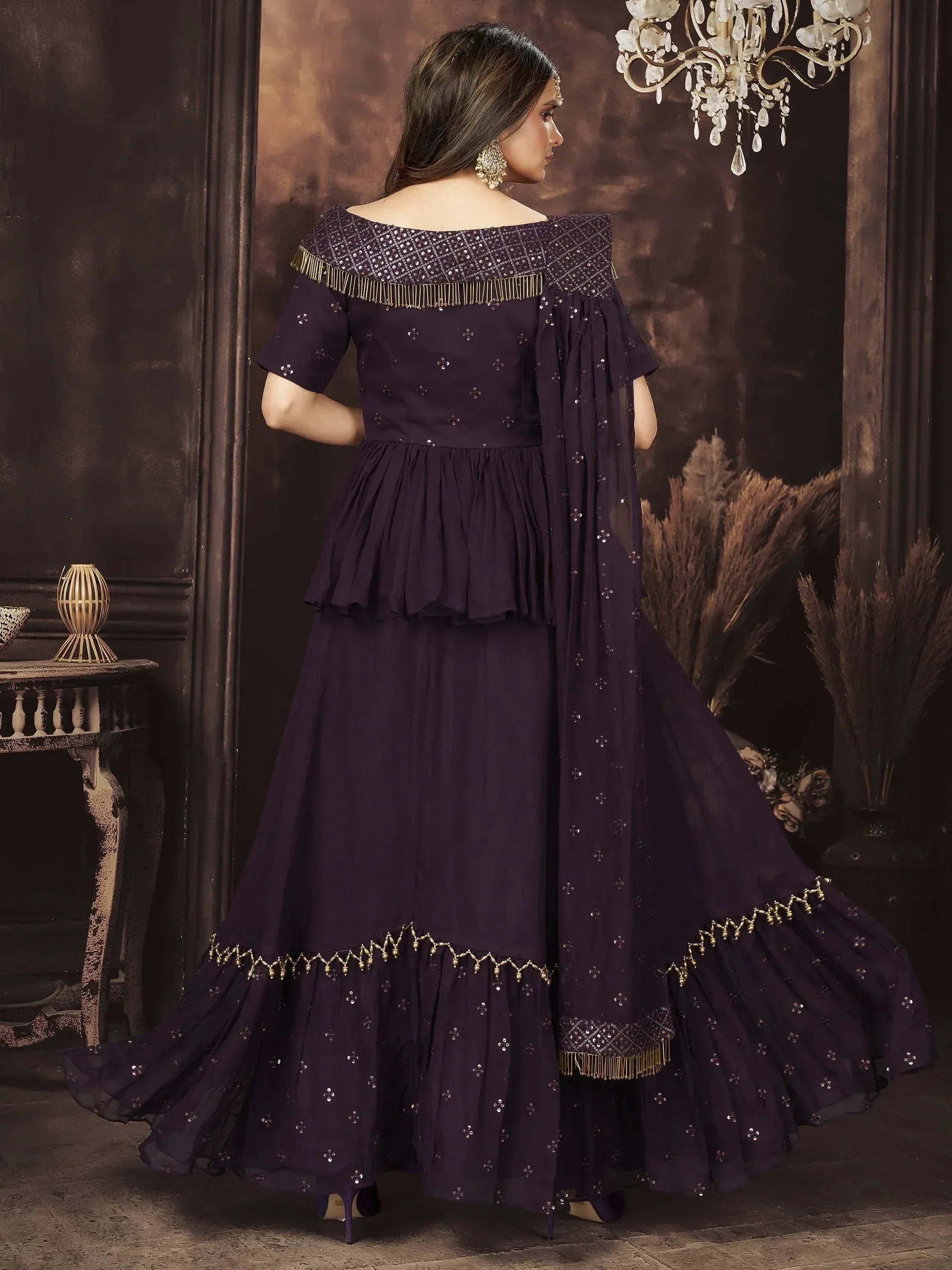 Elegant purple ethnic gown with off-shoulder design, gold fringe, and sequin detailing for festive occasions.