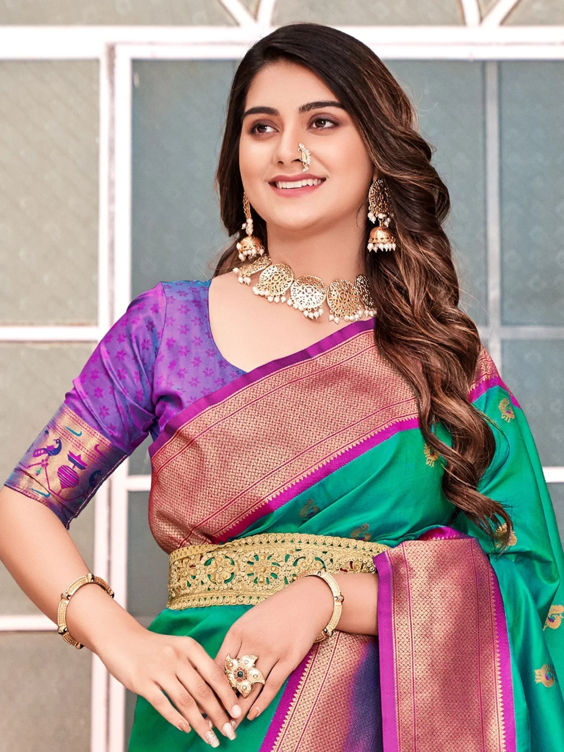 Woman in vibrant green and purple Indian saree with gold embroidery, traditional jewelry, and peacock motifs