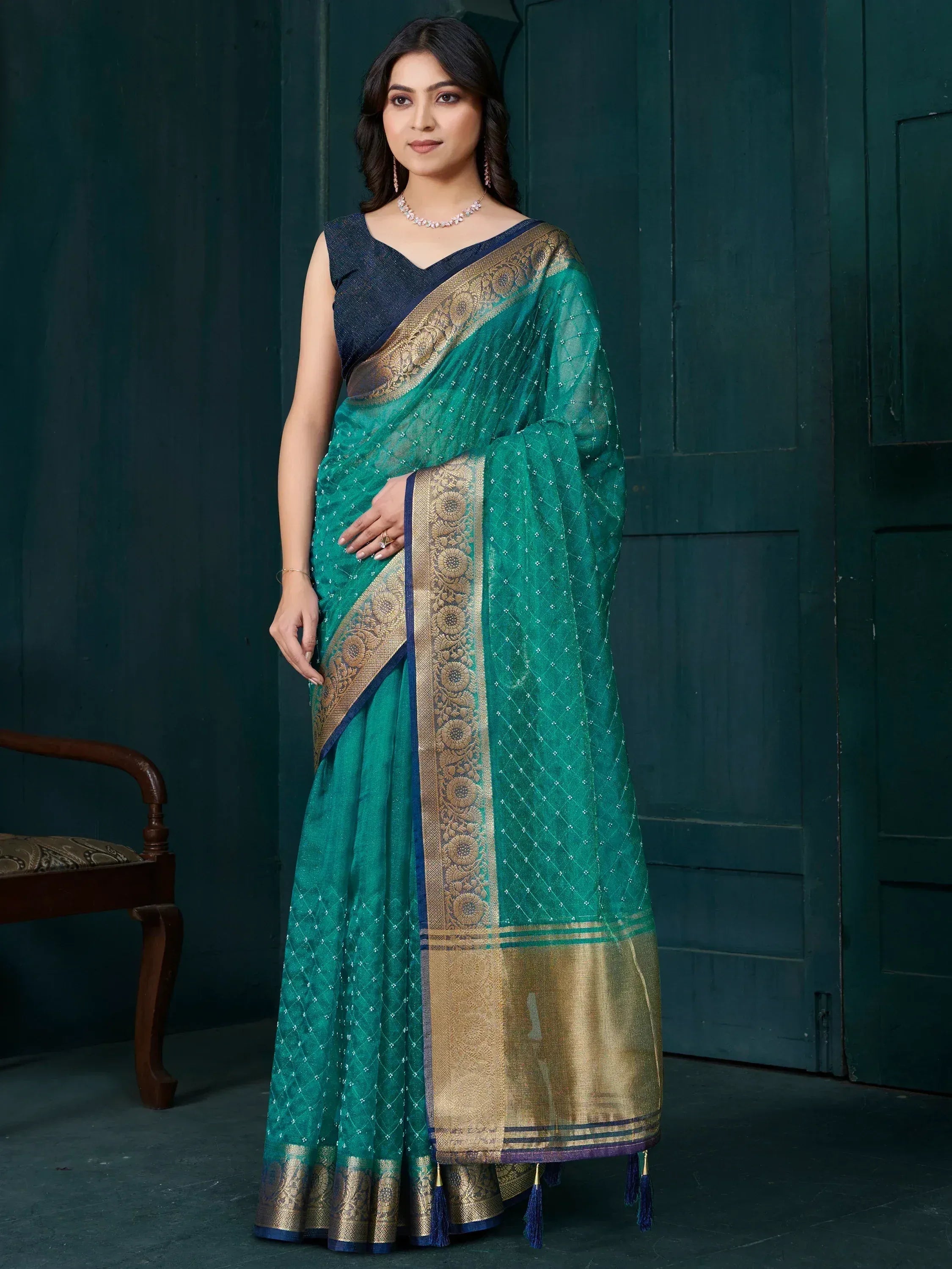 Elegant teal saree with golden border and intricate embroidery, paired with a navy blouse for festive occasions.