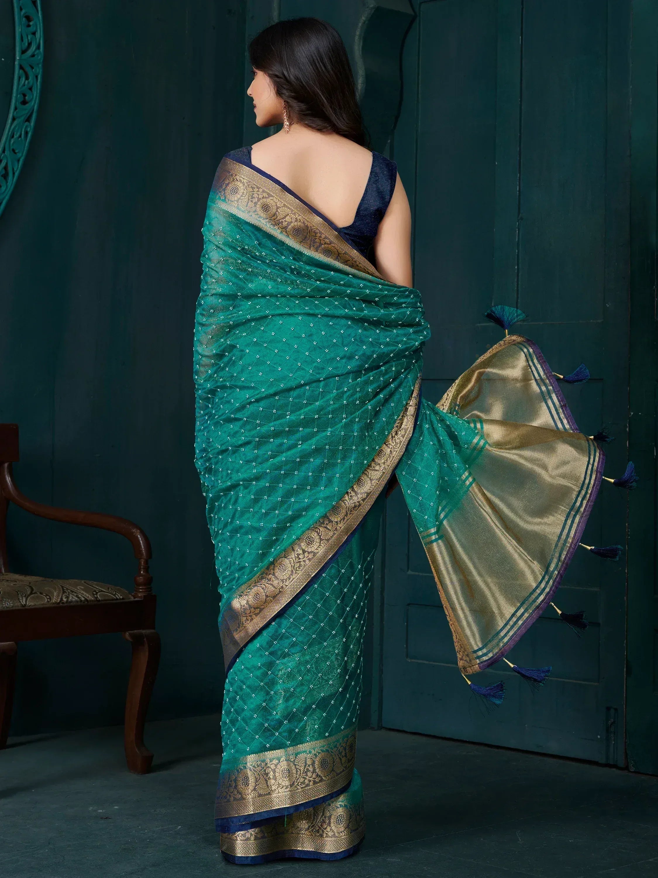 Teal saree with gold border and tassels, paired with navy blouse, showcasing ethnic Indian wear.