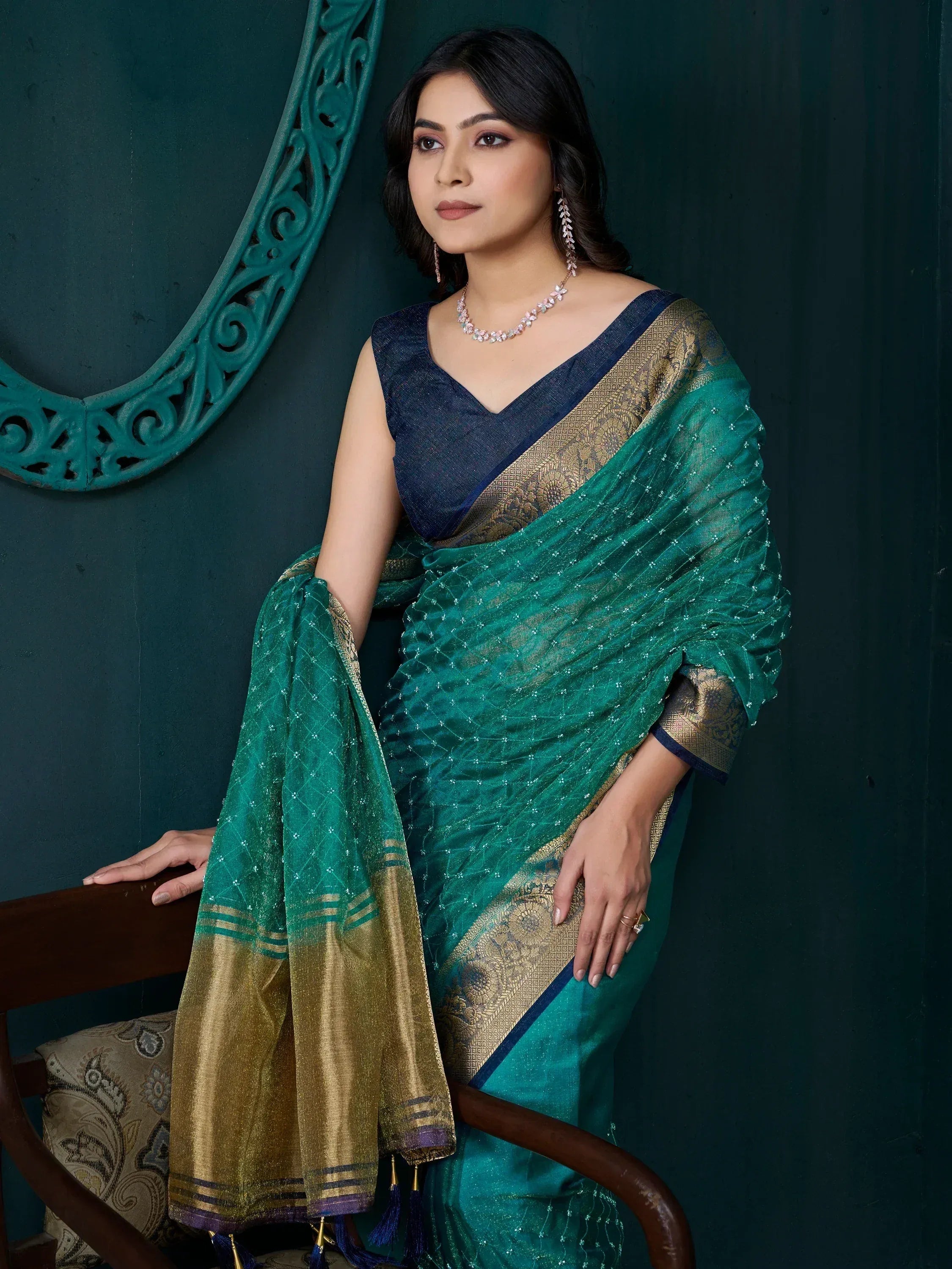 Elegant teal saree with gold border, styled with designer blouse and jewelry for ethnic wear.