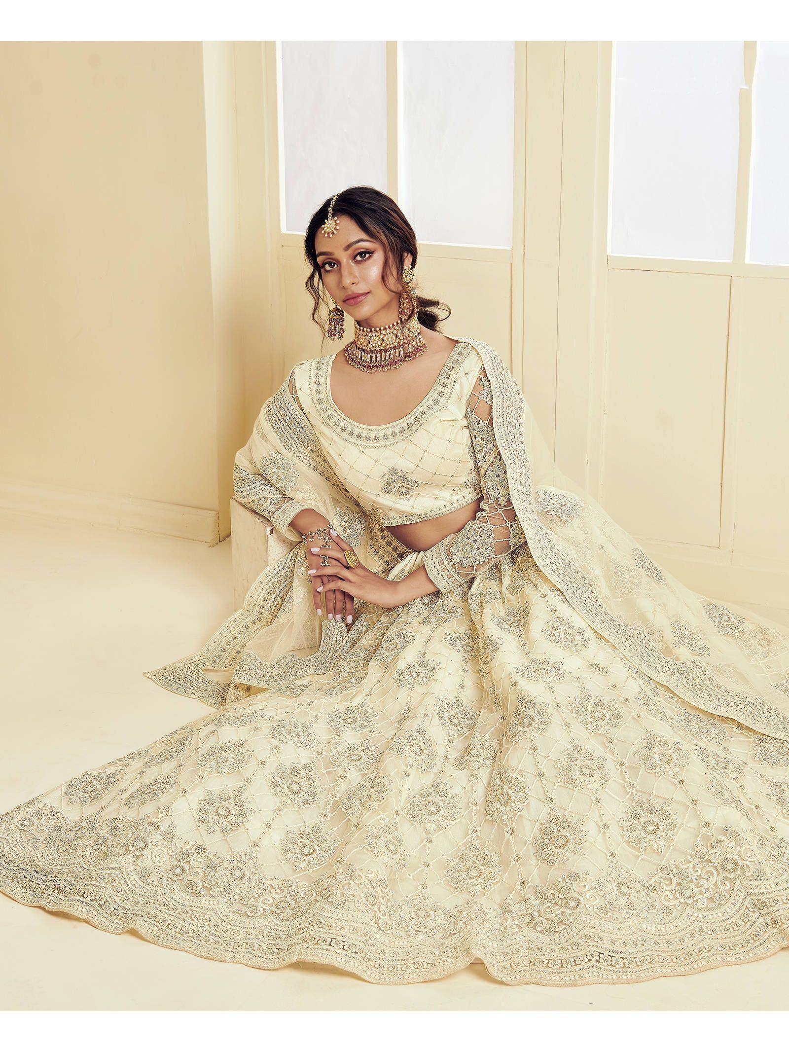Elegant cream lehenga choli with intricate gold embroidery, perfect for Indian weddings and festive occasions.