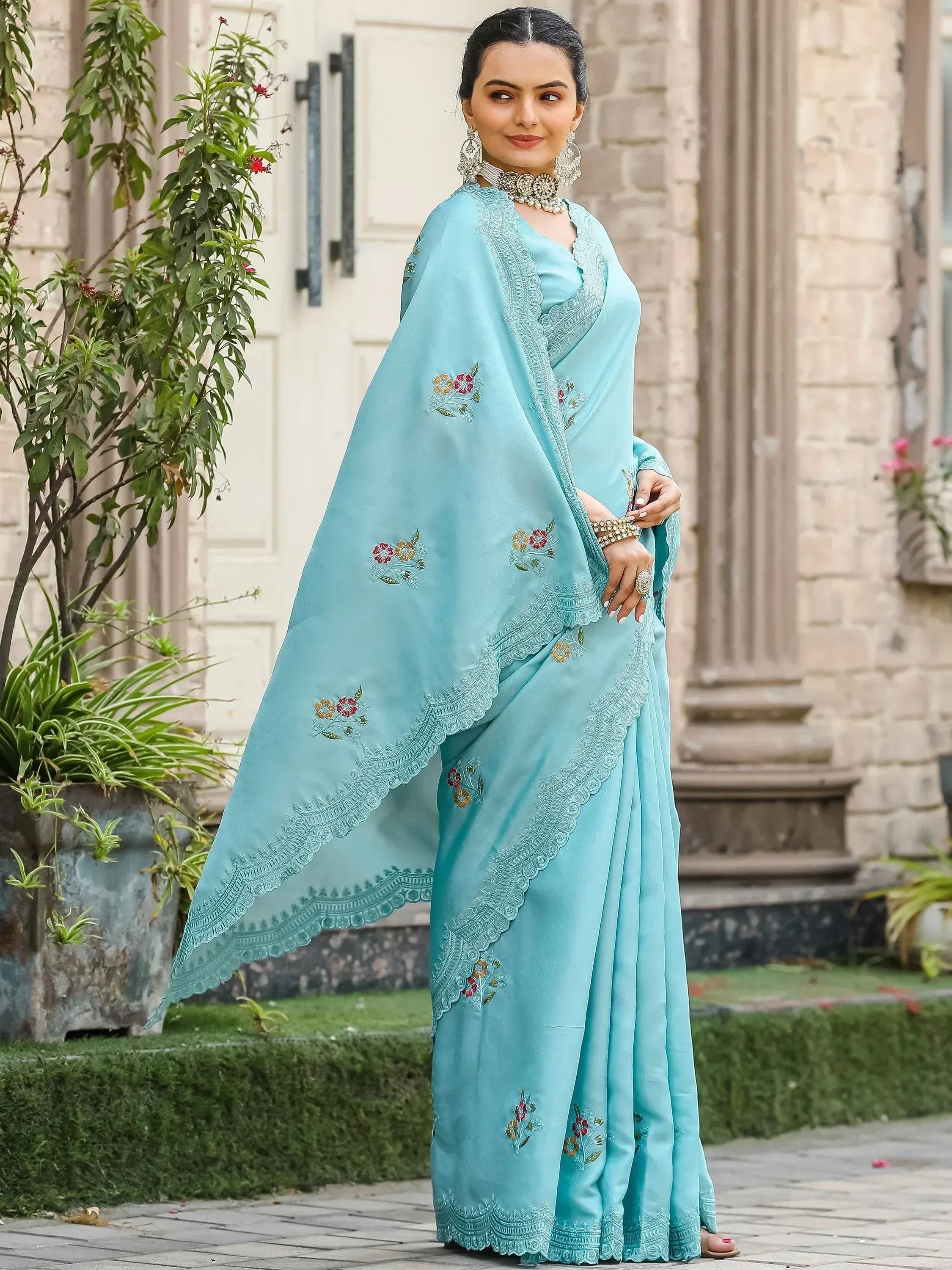 Light blue embroidered saree with floral motifs and lace border, styled with traditional jewelry for ethnic wear.
