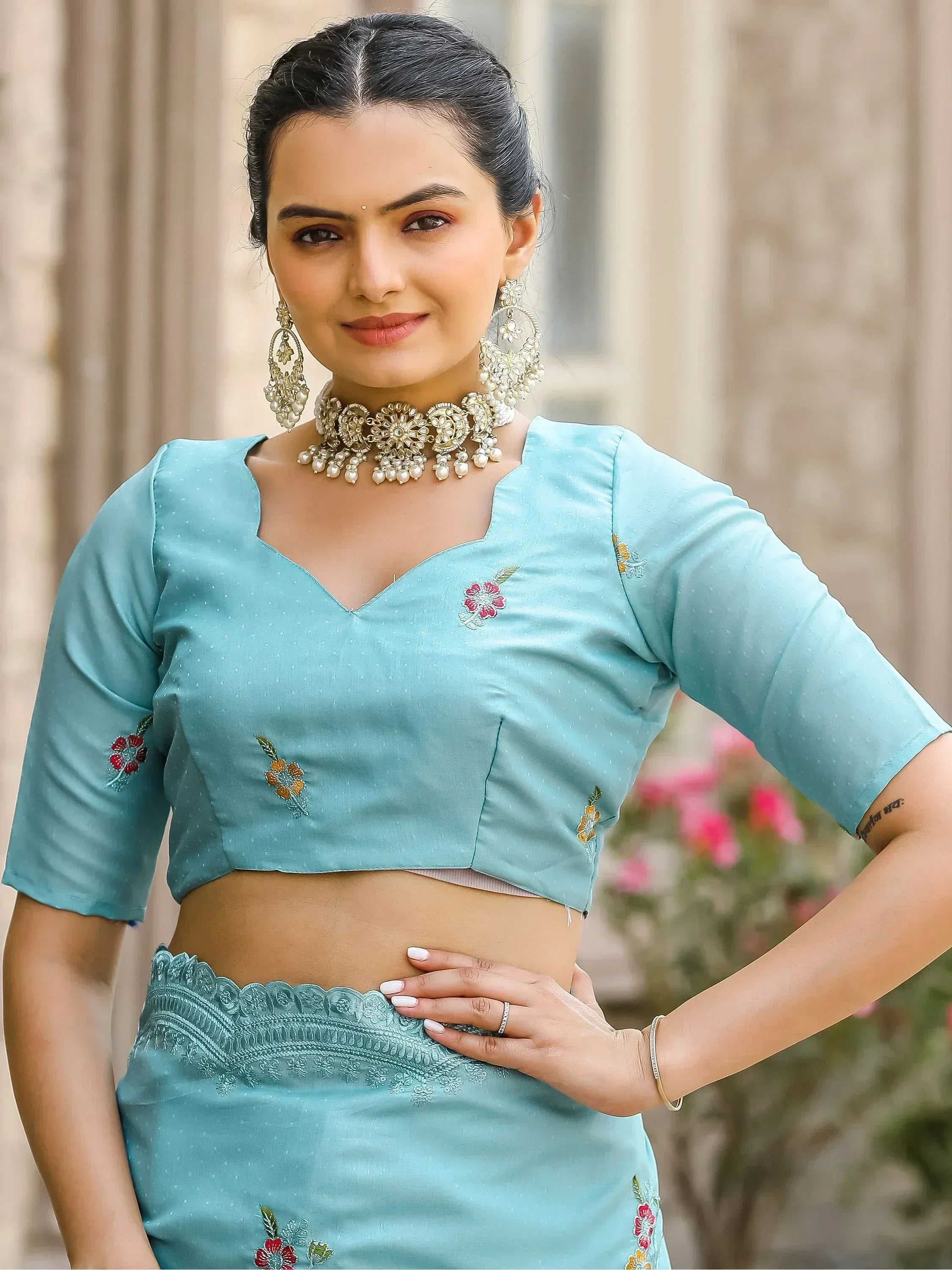 Light blue embroidered lehenga choli with floral details and pearl jewelry for Indian ethnic wear