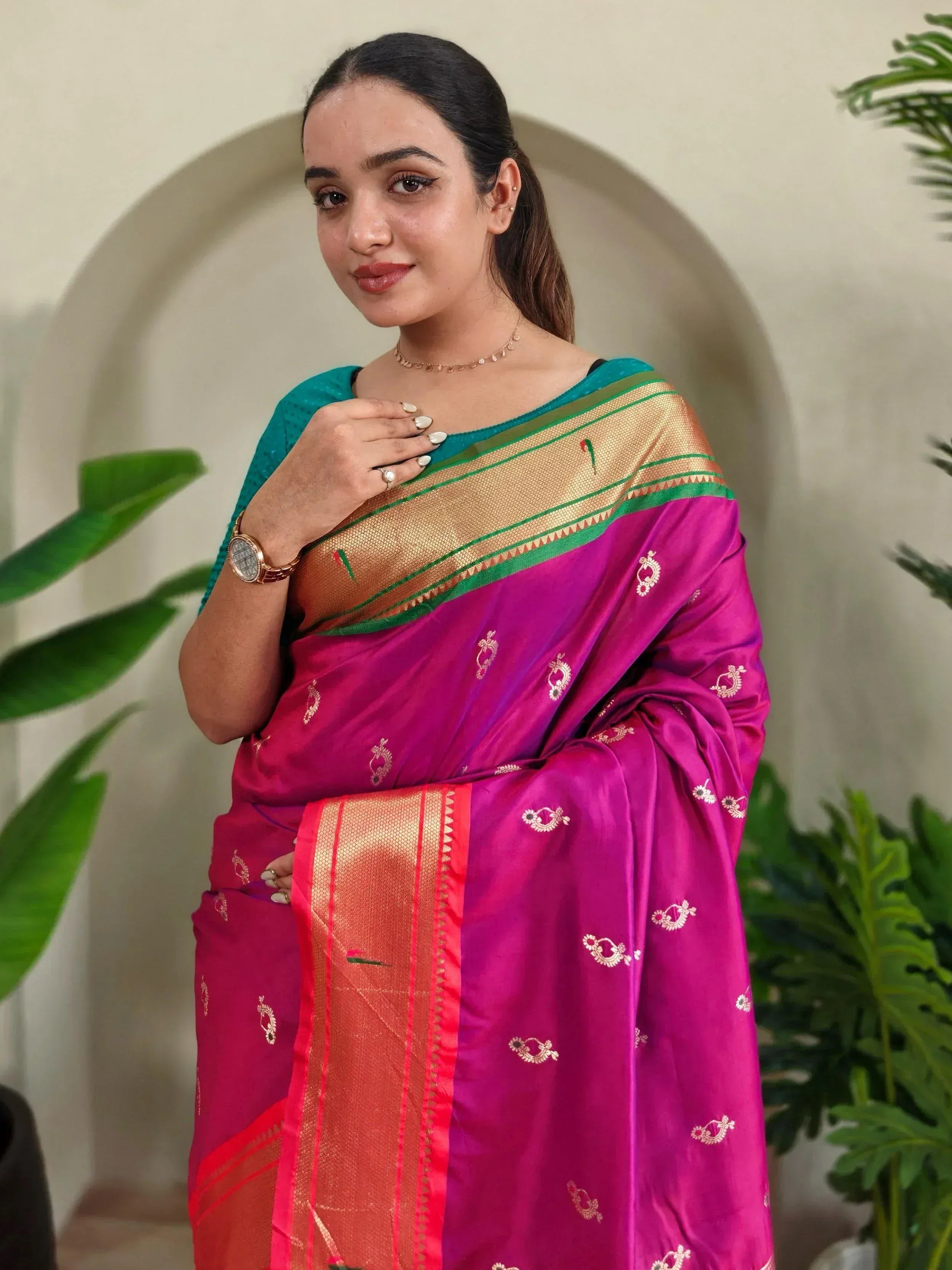 Woman in vibrant pink silk saree with gold border and teal blouse, ethnic Indian wear