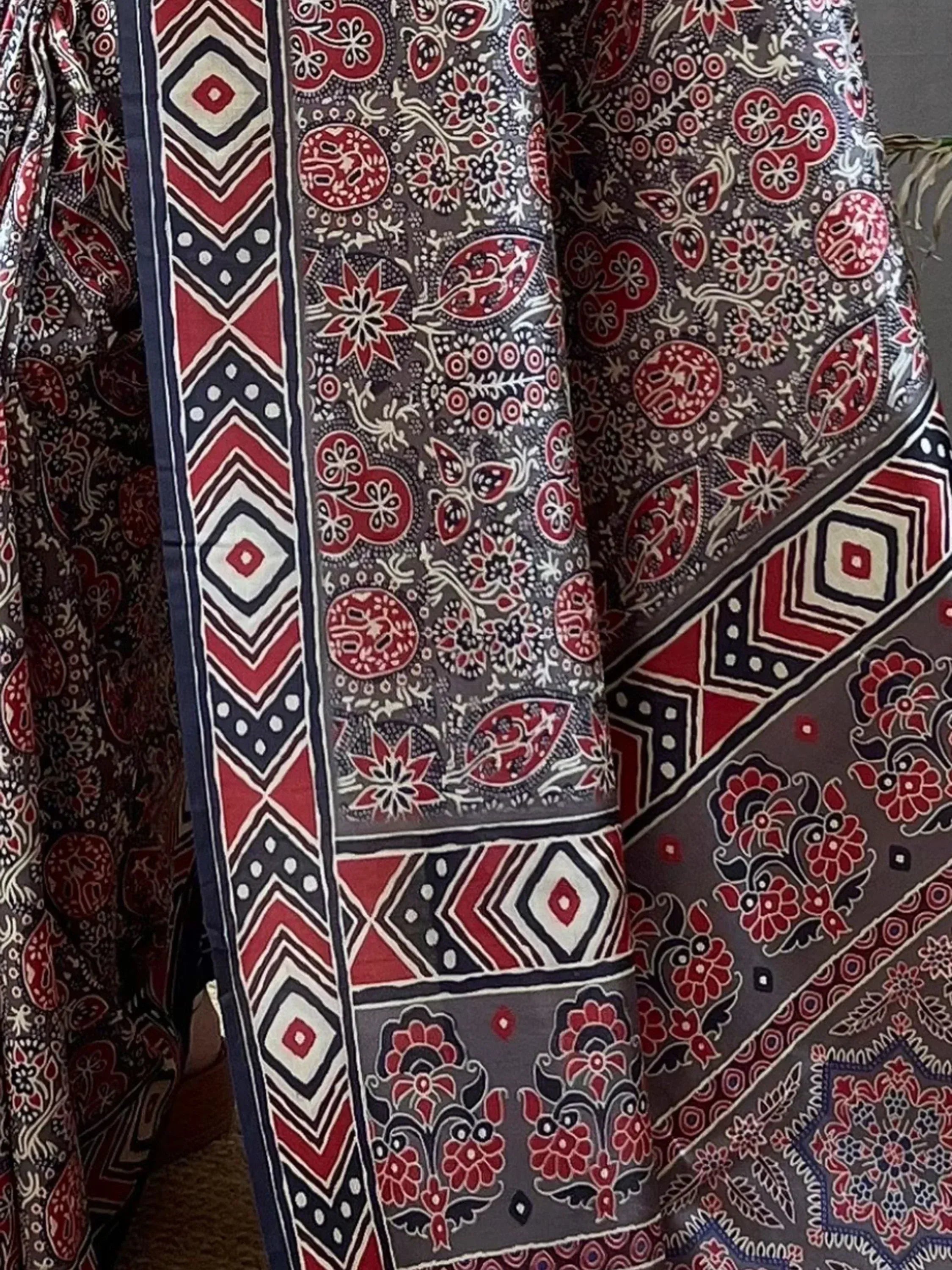 Ethnic printed saree with red, black, and white floral and geometric patterns, ideal for traditional wear.