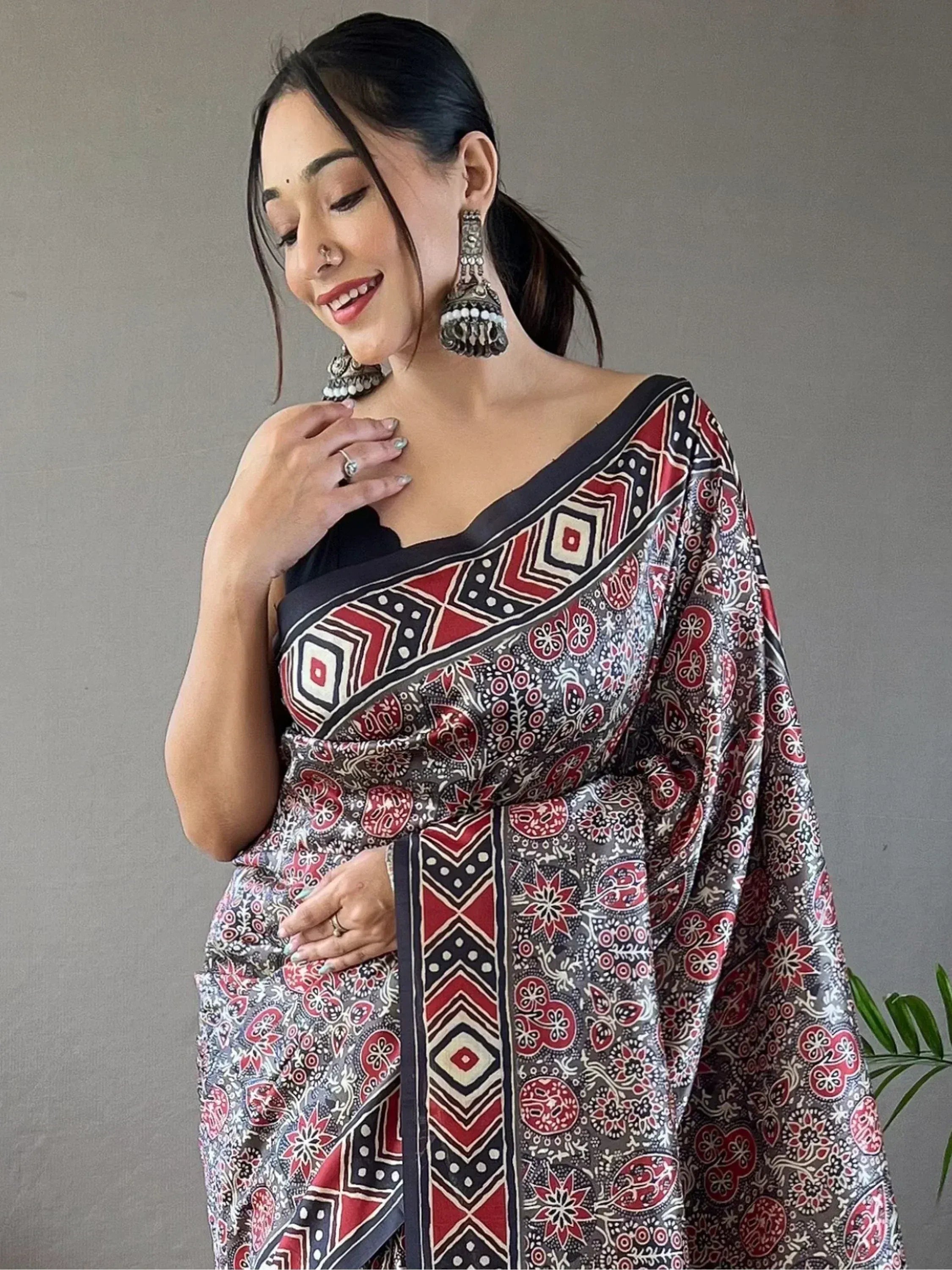 Woman in elegant ethnic saree with red and black geometric print, styled with jhumka earrings for festive occasions