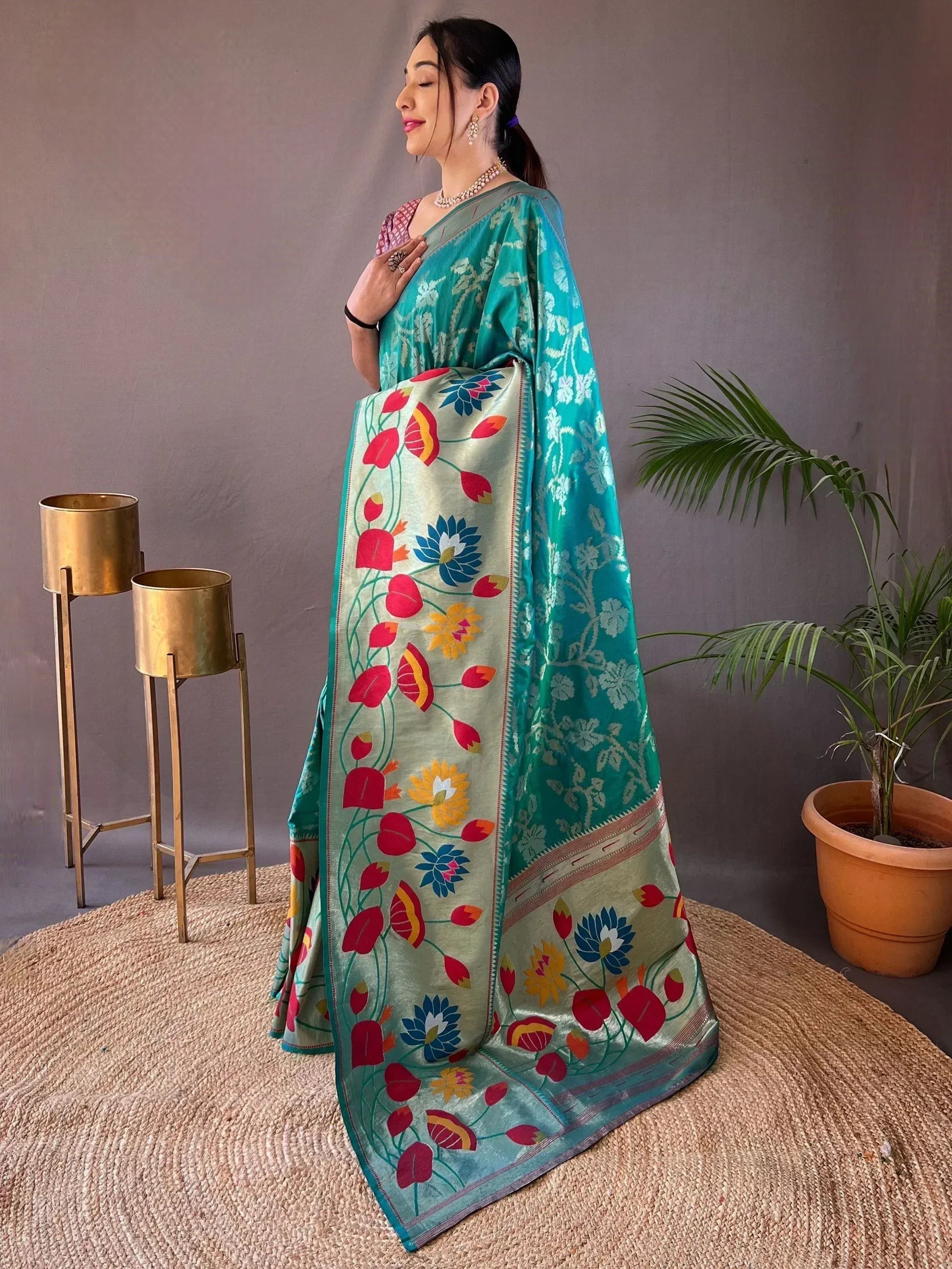 Woman in teal floral printed saree with vibrant border, ethnic Indian wear