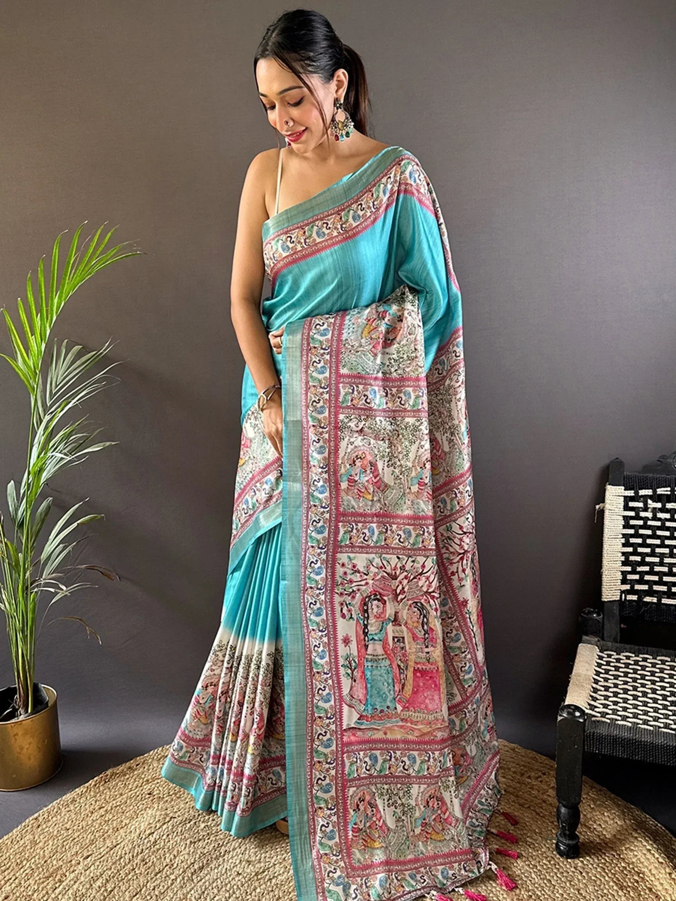 Woman in turquoise designer saree with intricate ethnic print and tassels, perfect for Indian occasions.