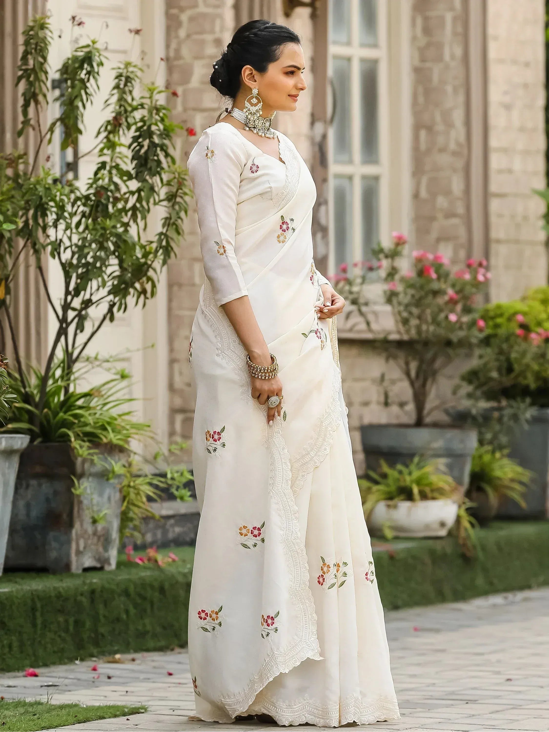 White embroidered saree with floral motifs and lace detailing, paired with statement jewelry for ethnic occasions.