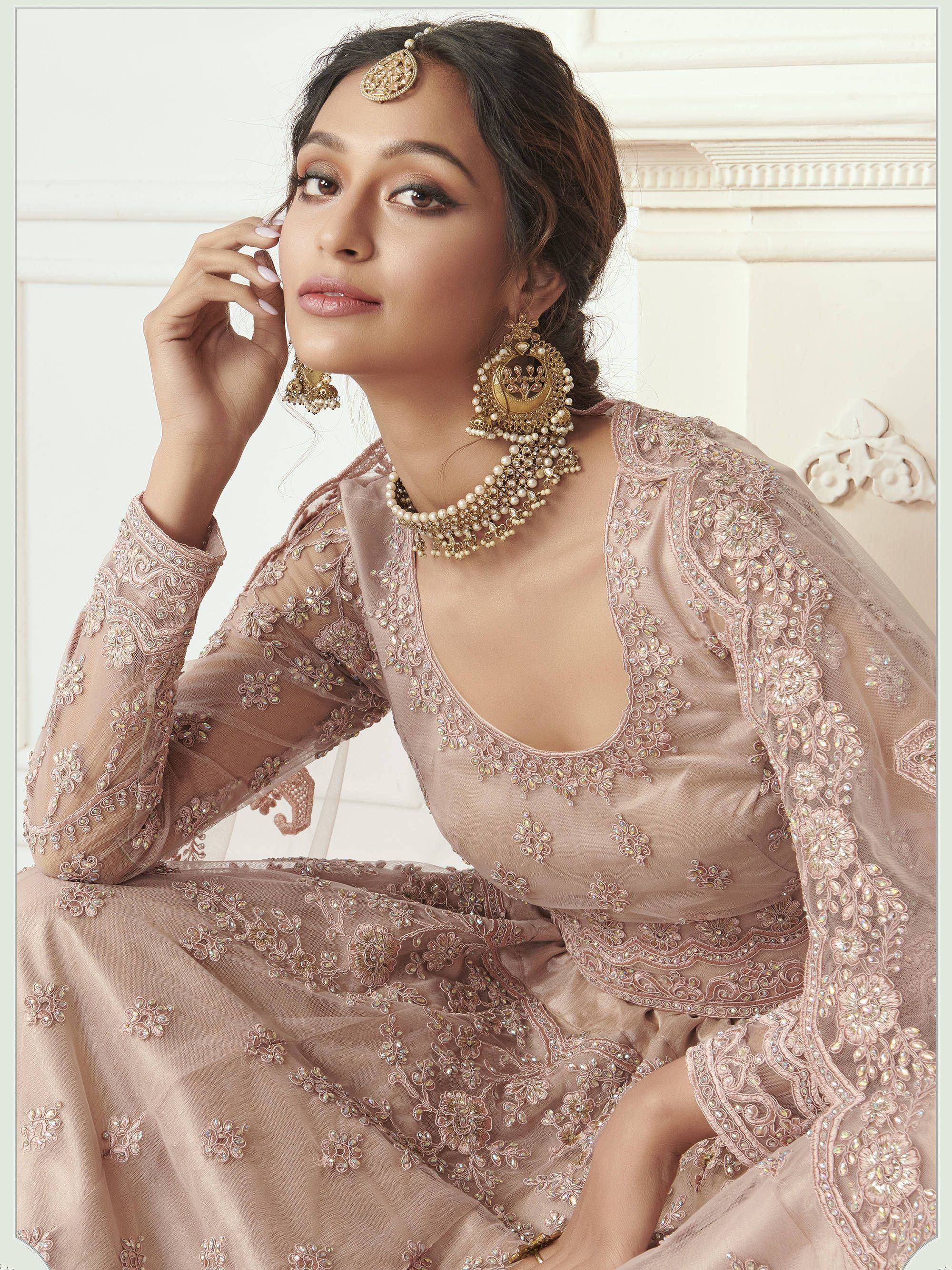 Elegant blush pink embroidered lehenga choli with gold jewelry, perfect for Indian weddings and festive occasions.