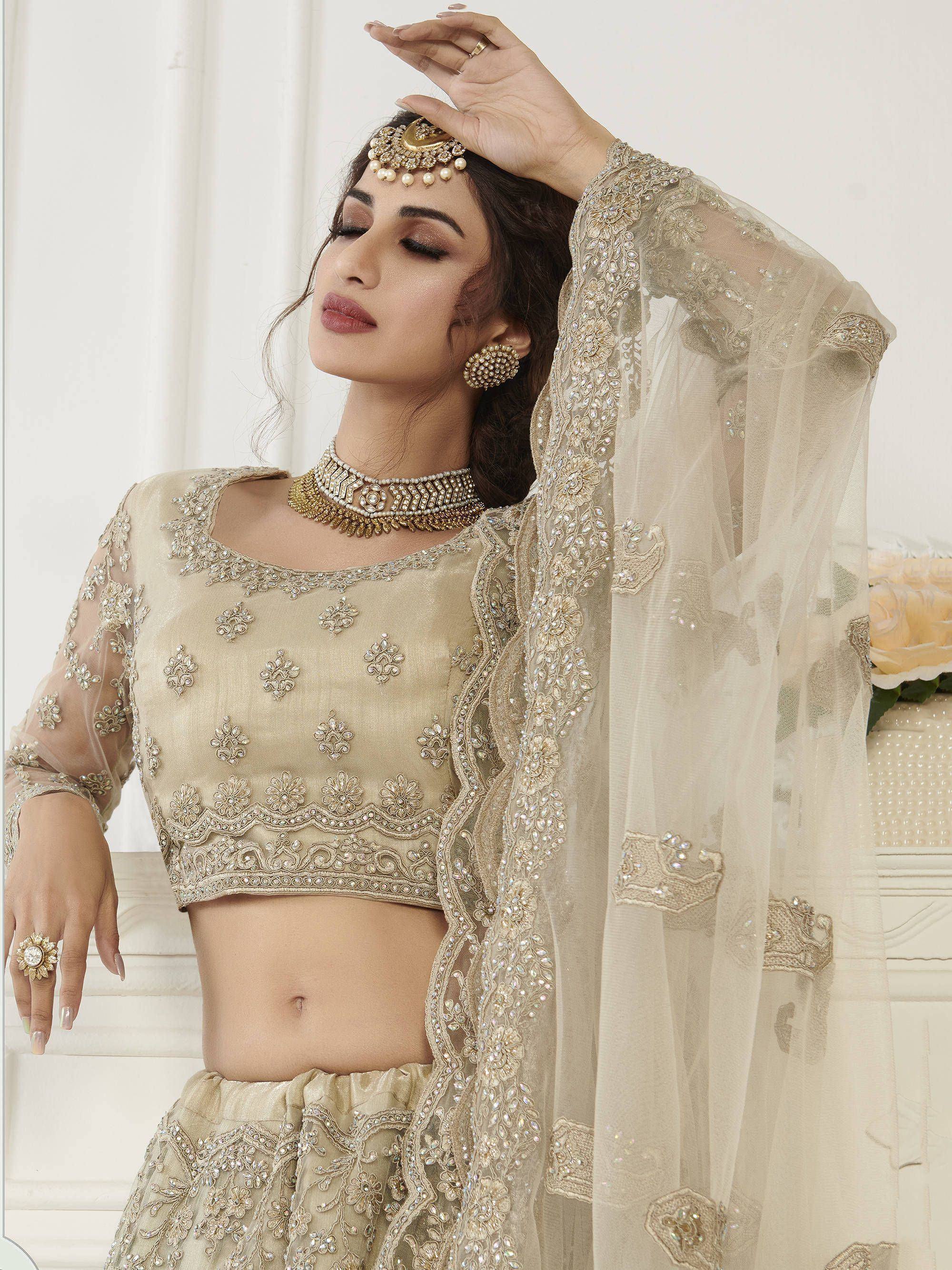 Elegant beige embroidered lehenga choli with sheer dupatta, perfect for Indian weddings and festive occasions.