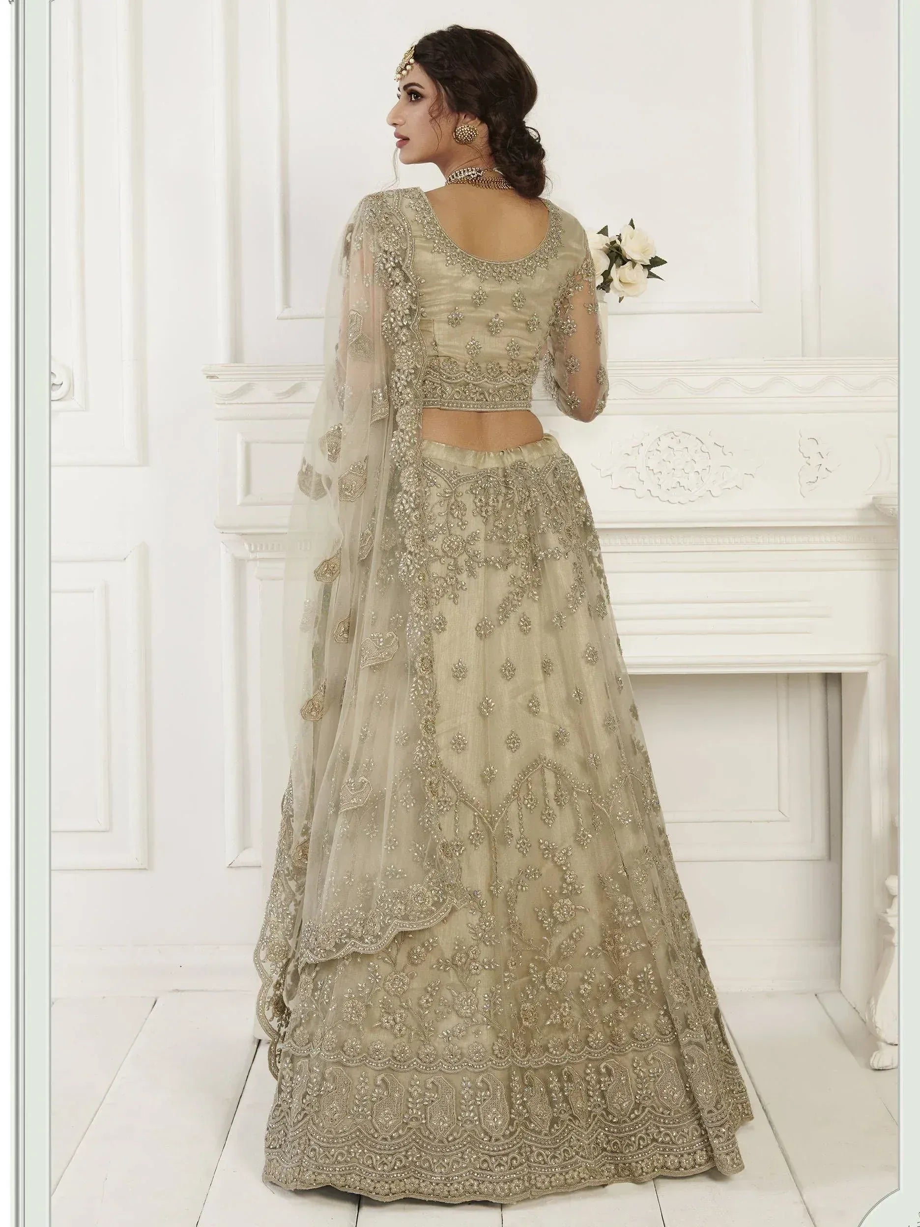 Elegant beige designer lehenga choli with intricate gold embroidery and sheer dupatta, perfect for Indian weddings.