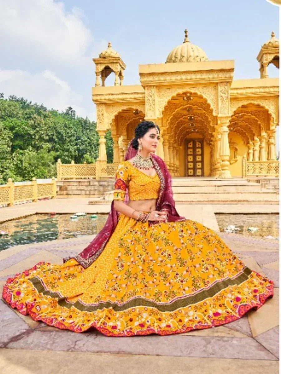 Yellow floral lehenga choli with maroon dupatta, worn at a golden palace, perfect for Indian ethnic occasions.