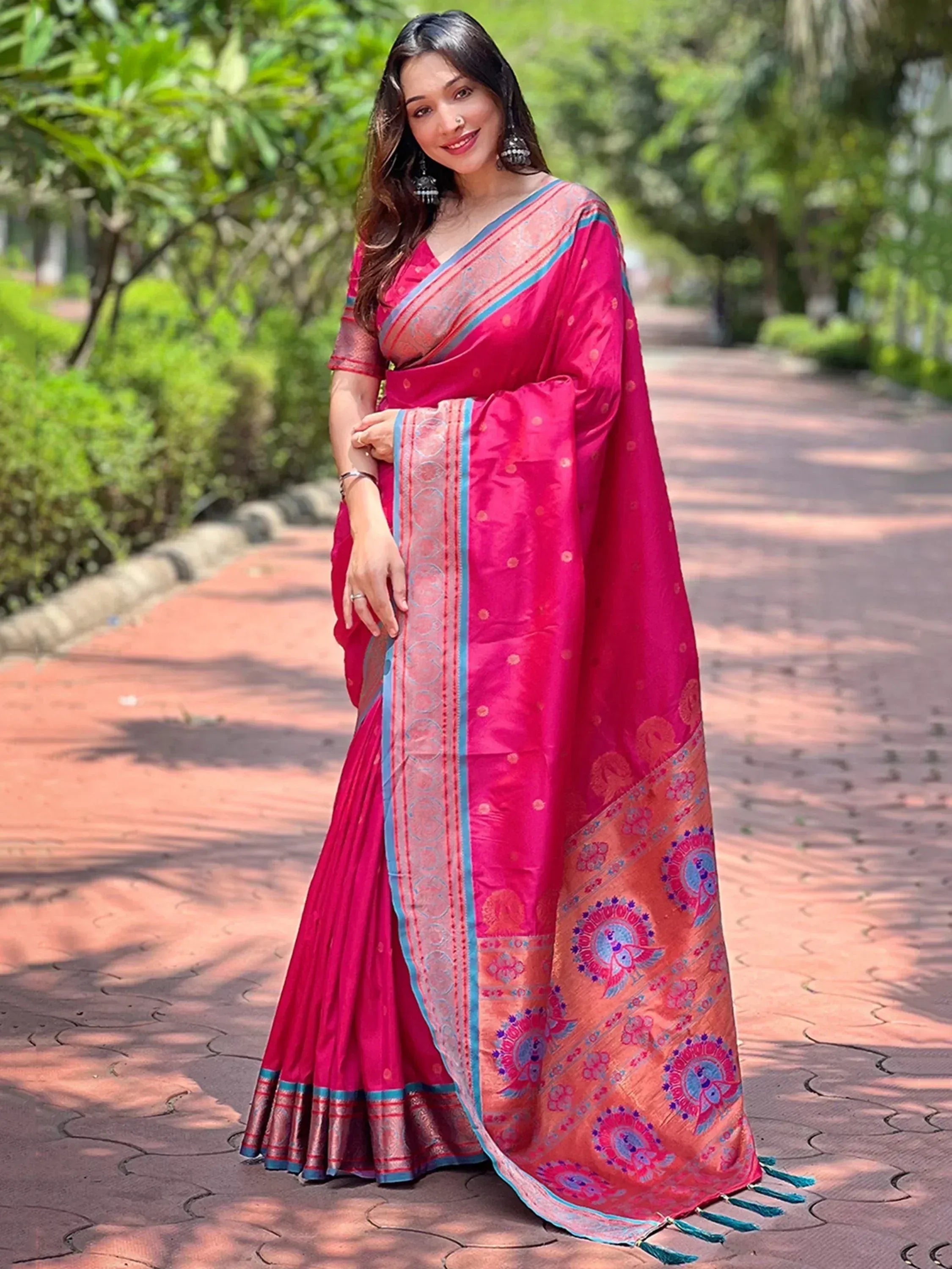 Vibrant pink Indian saree with peacock motifs and blue border, styled for ethnic occasions
