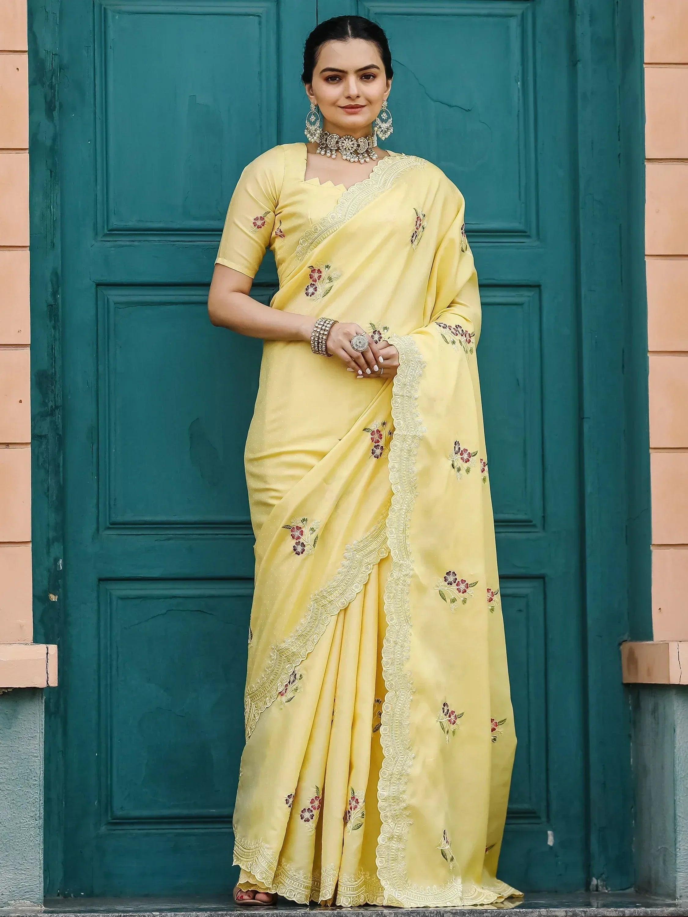 Yellow embroidered saree with floral motifs and lace border, styled with traditional jewelry
