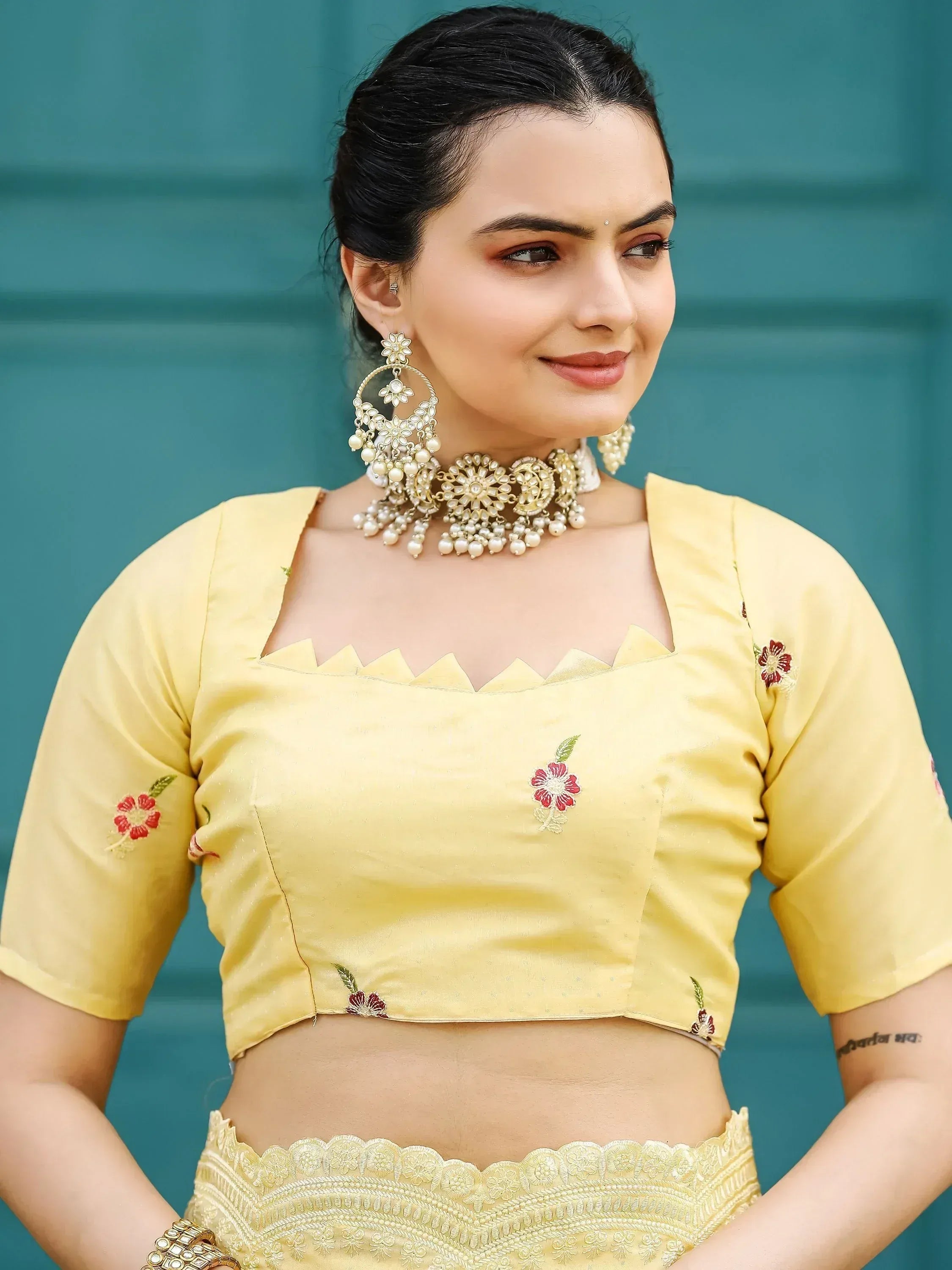 Yellow embroidered lehenga choli with floral motifs and pearl jewelry, perfect for Indian ethnic wear.