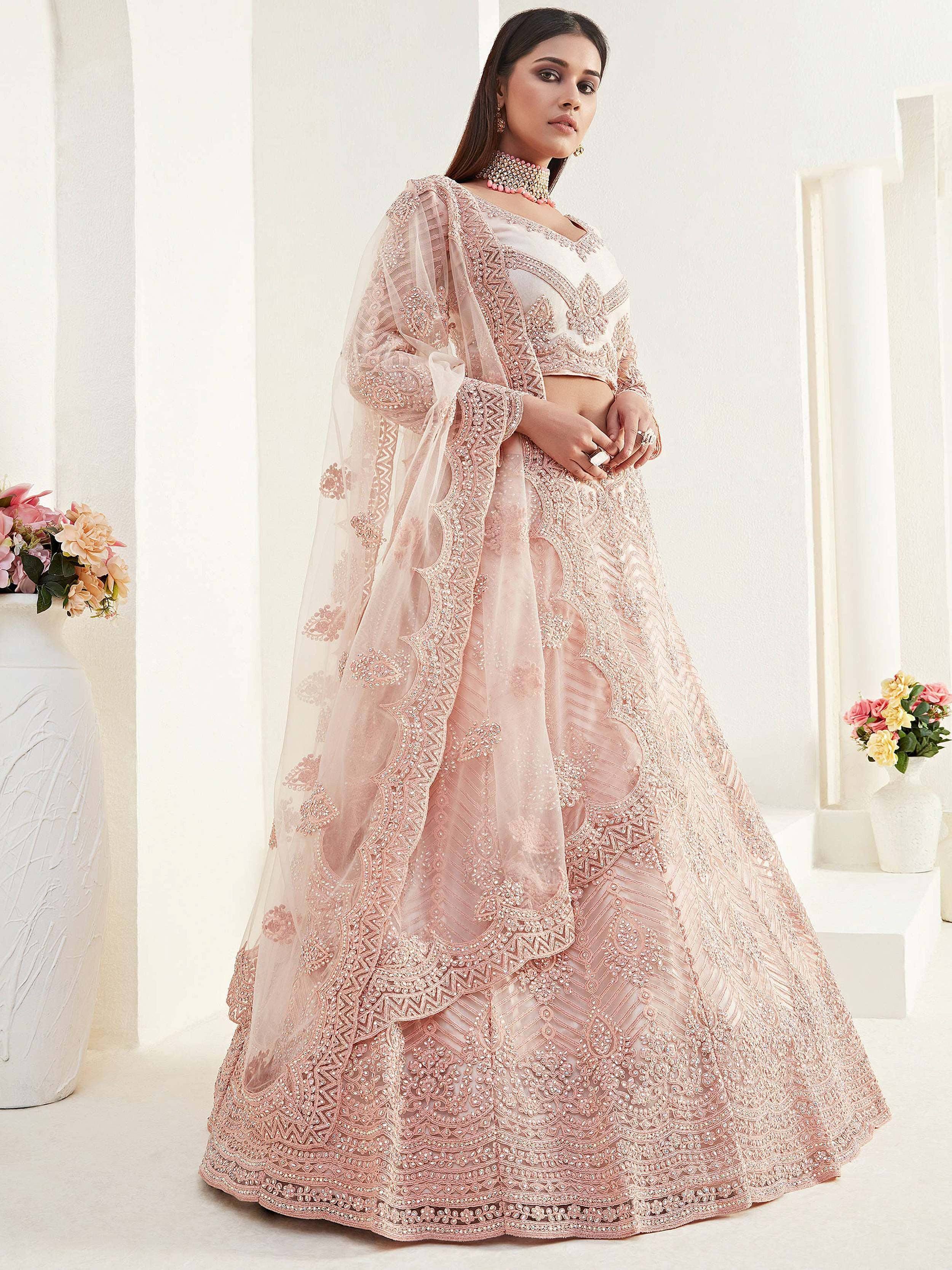 Elegant blush pink designer lehenga choli with intricate embroidery and sheer dupatta, perfect for weddings and festive occasions.