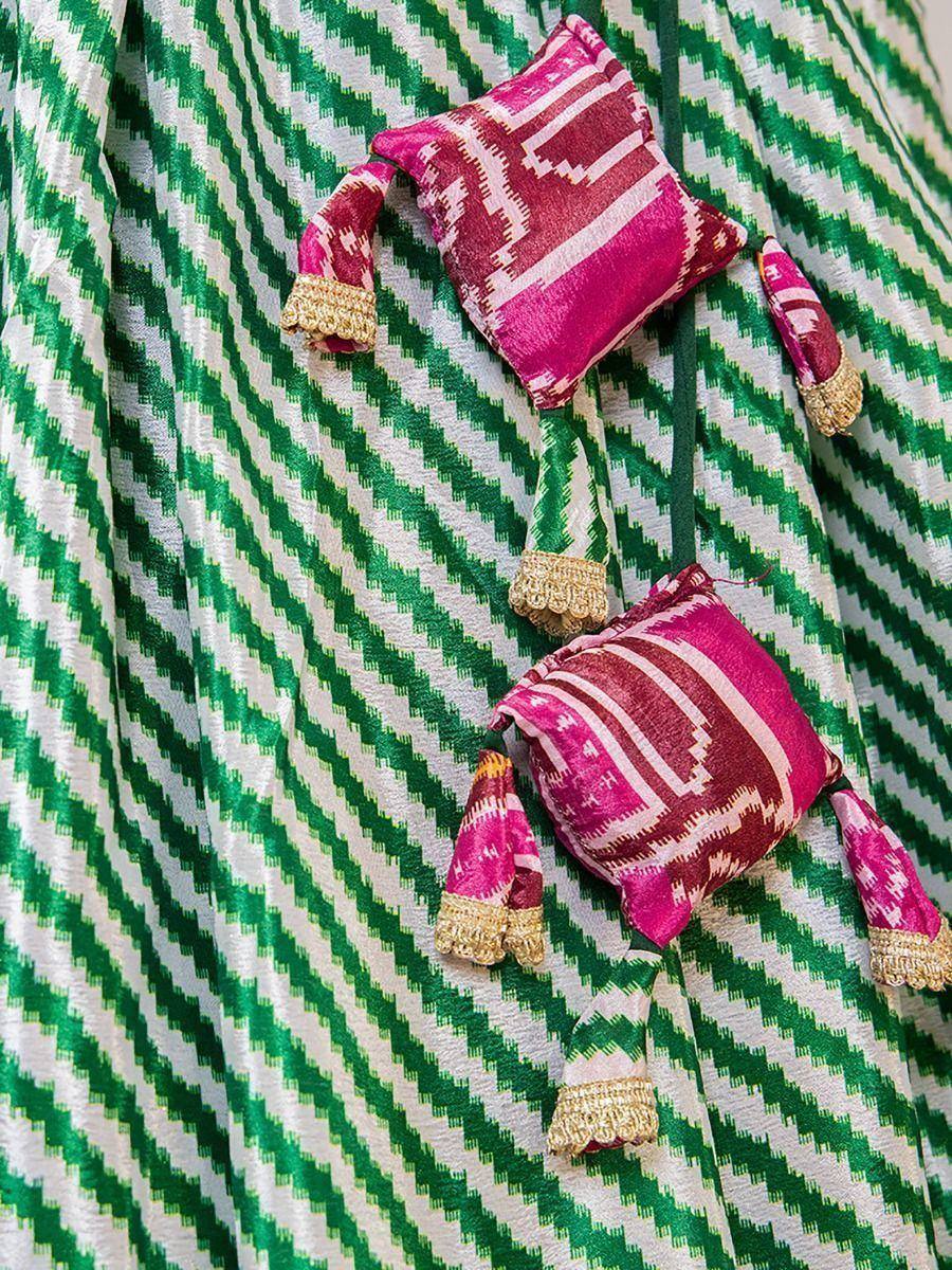 Green and white zigzag patterned ethnic gown with pink ikat tassels and gold trim details