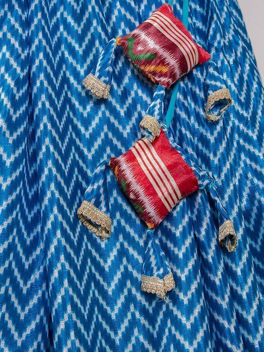 Blue ikat print ethnic skirt with red striped pouches and gold tassels, perfect for Indian festive wear