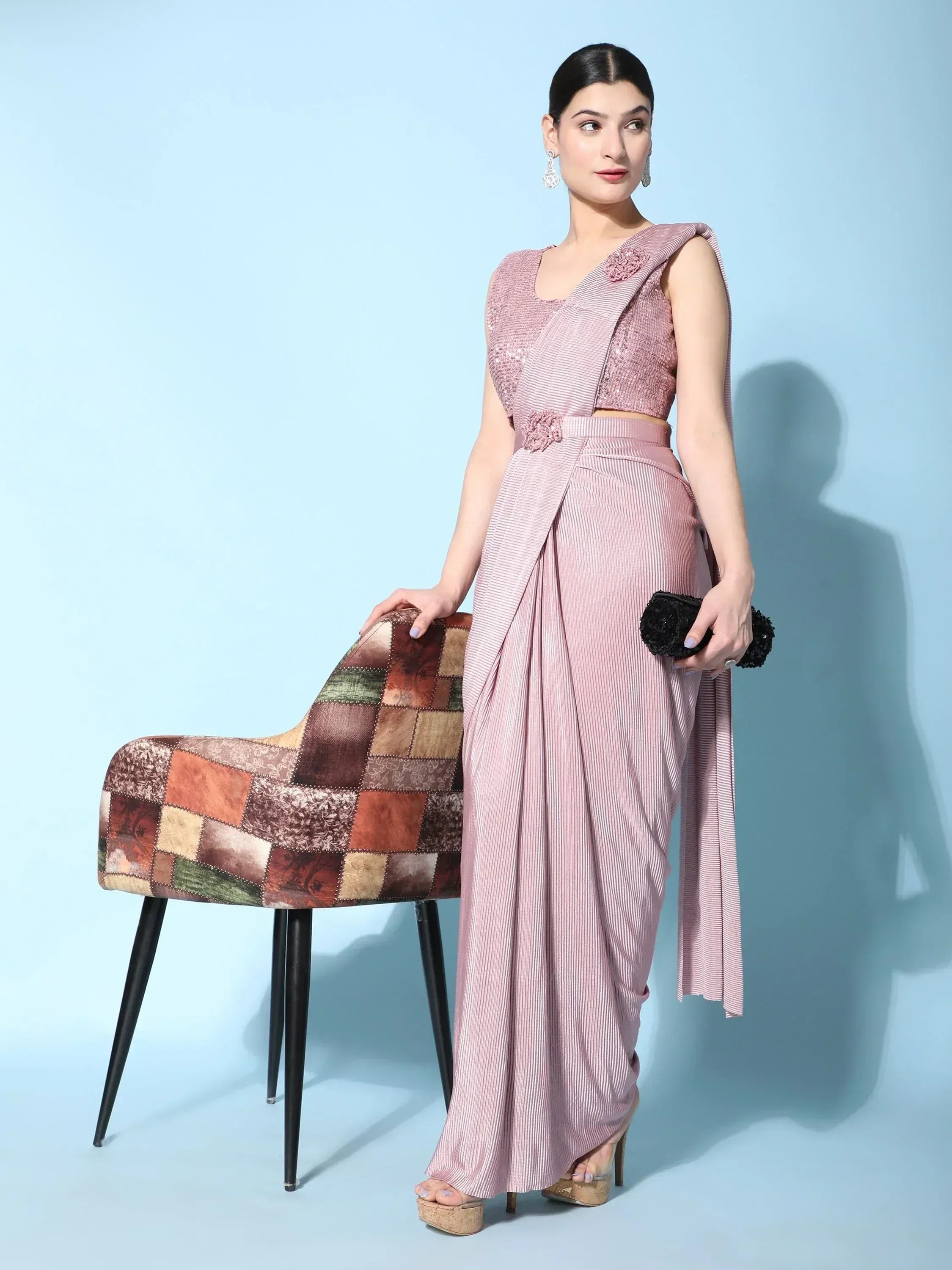 Elegant pink striped dhoti saree with floral embellishments, paired with high heels and a clutch