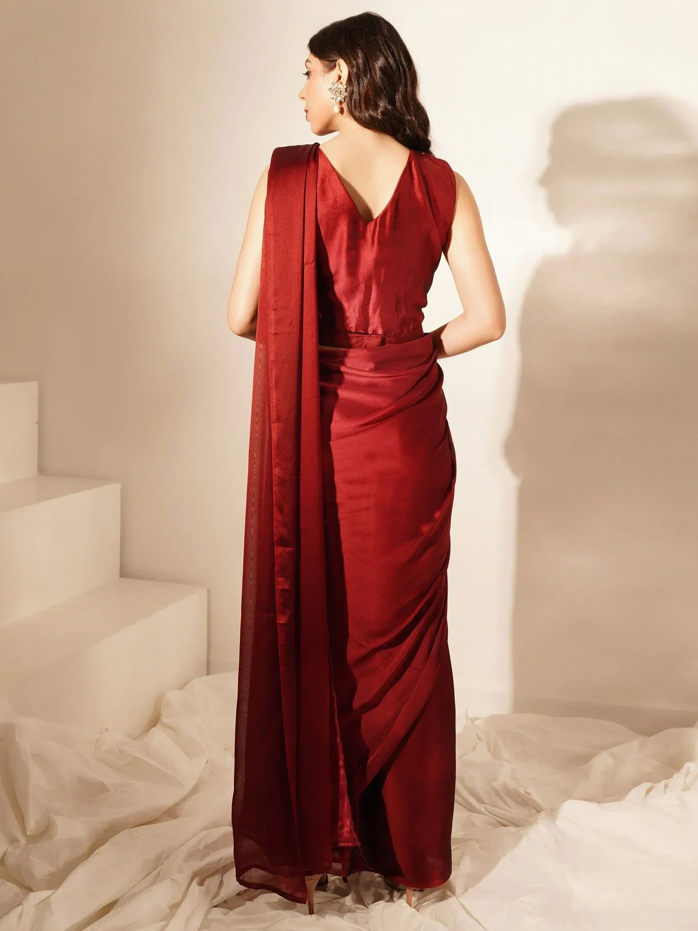 Woman in elegant maroon satin saree with draped back, perfect for Indian ethnic occasions