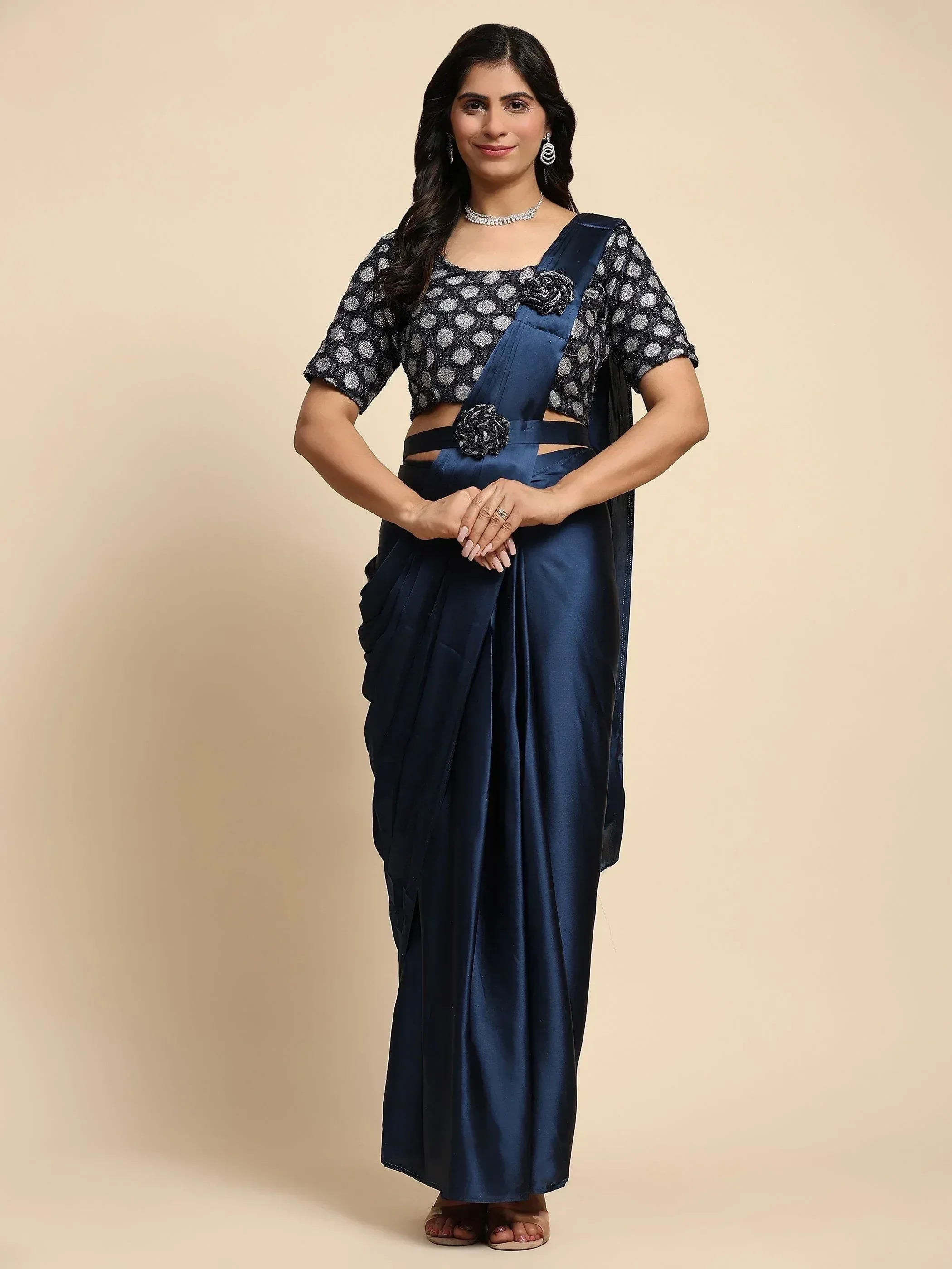 Navy blue satin saree with polka dot blouse, floral embellishments, and cut-out waist detail for ethnic wear