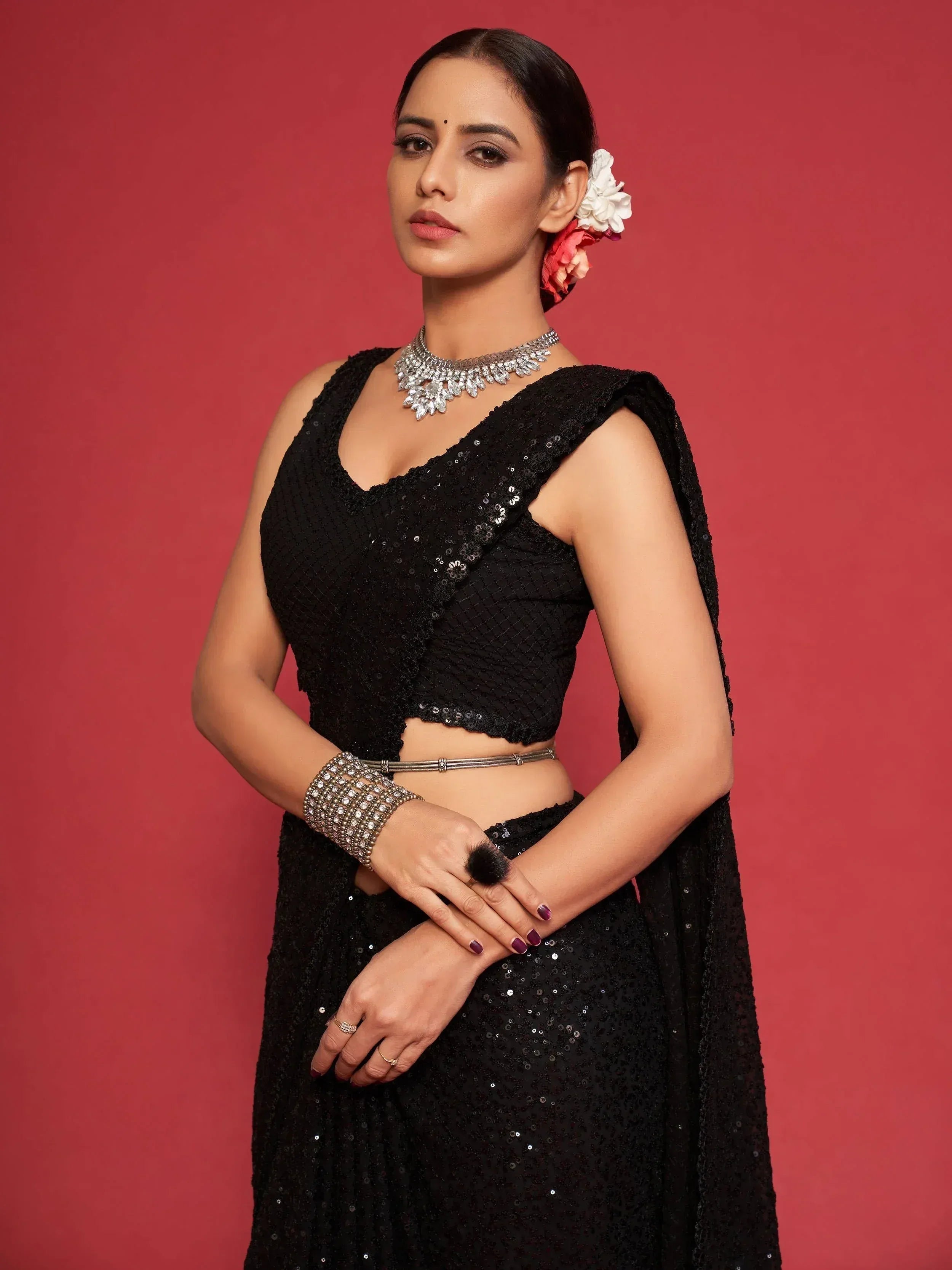 Black sequin lehenga choli with statement jewelry and floral hair accessory for Indian ethnic wear