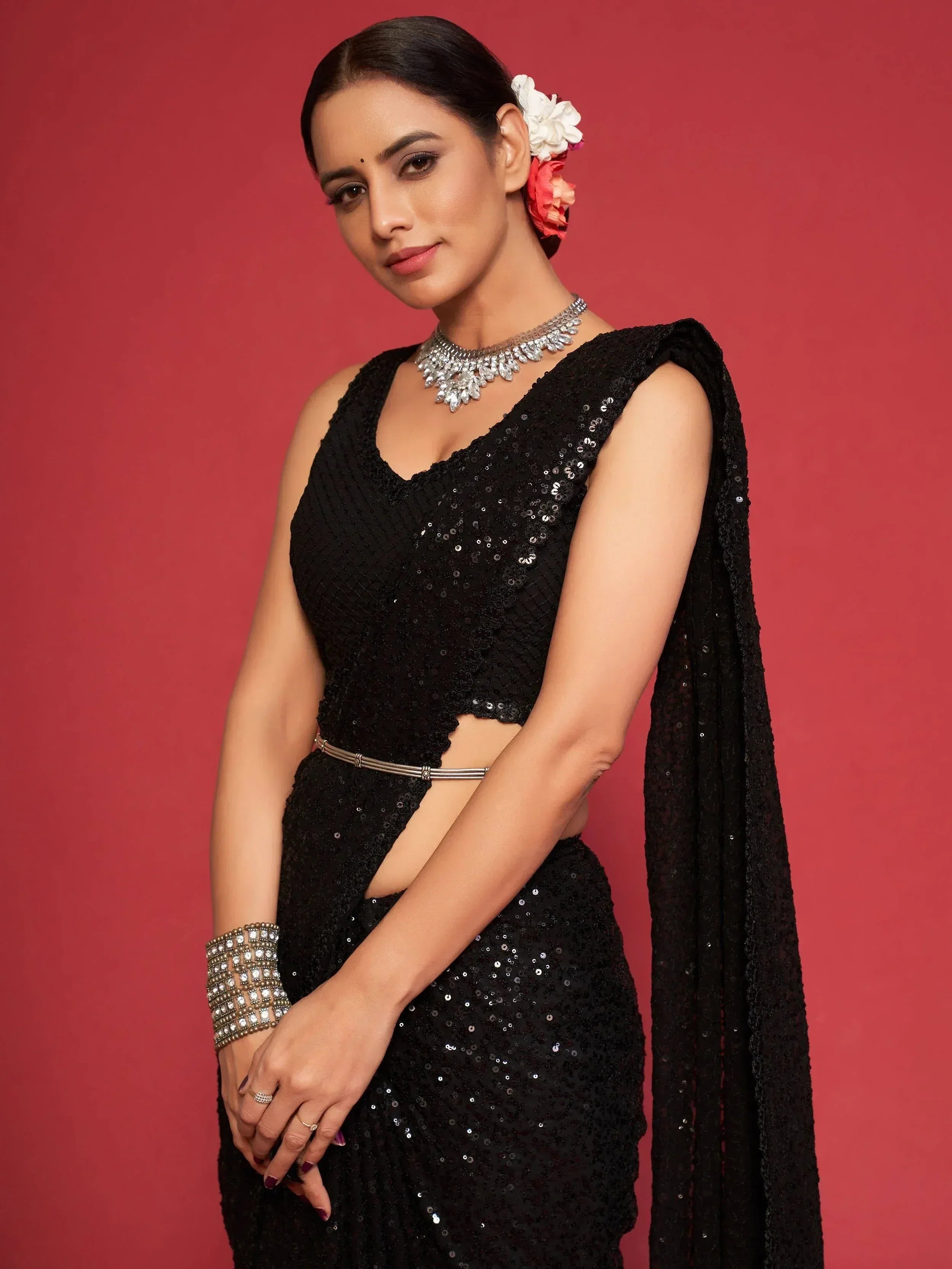 Black sequin saree with designer blouse and floral hair accessory, perfect for Indian ethnic occasions.