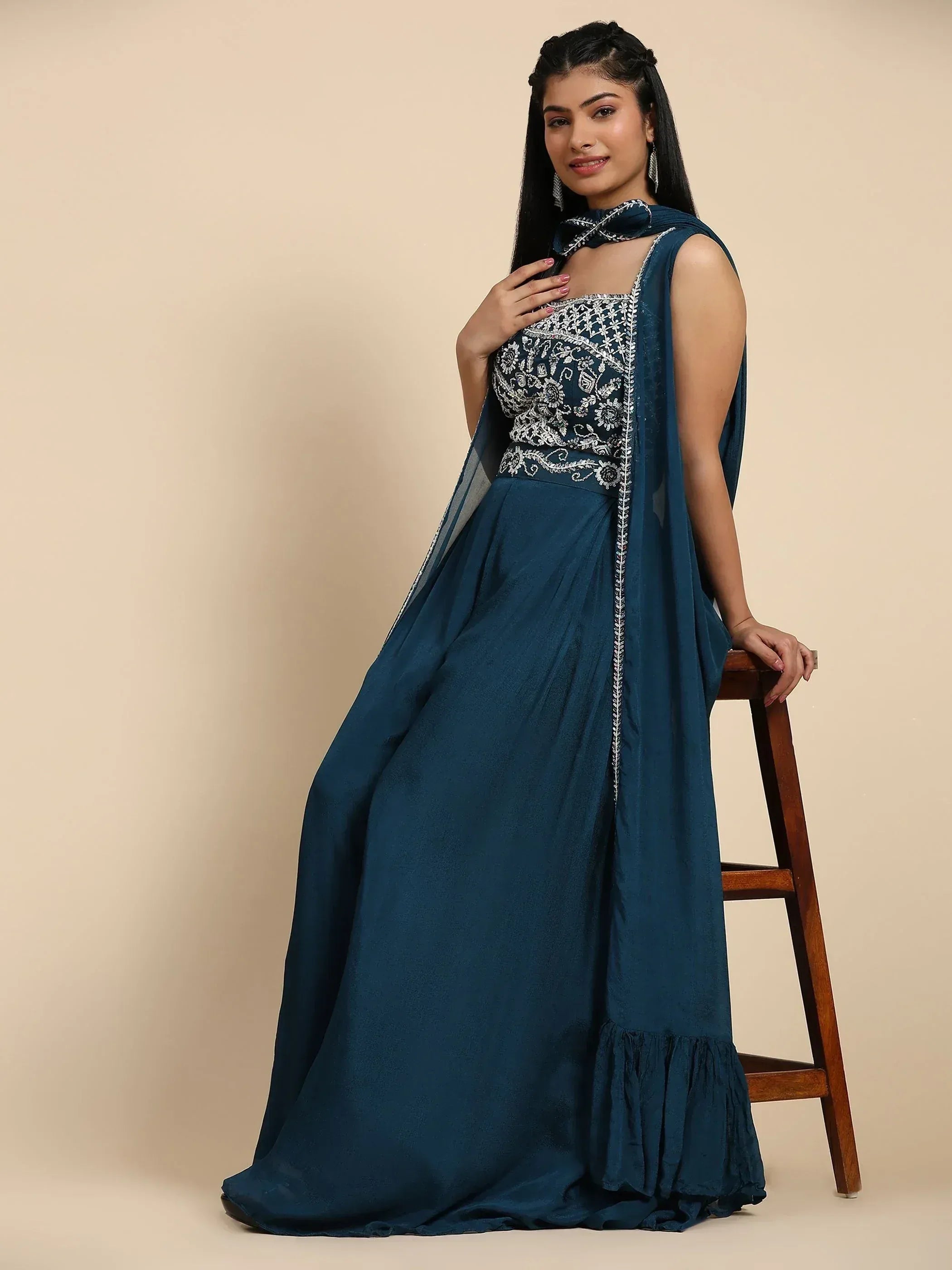 Teal ethnic gown with silver embroidery, sheer cape, and ruffled hem for Indian occasions
