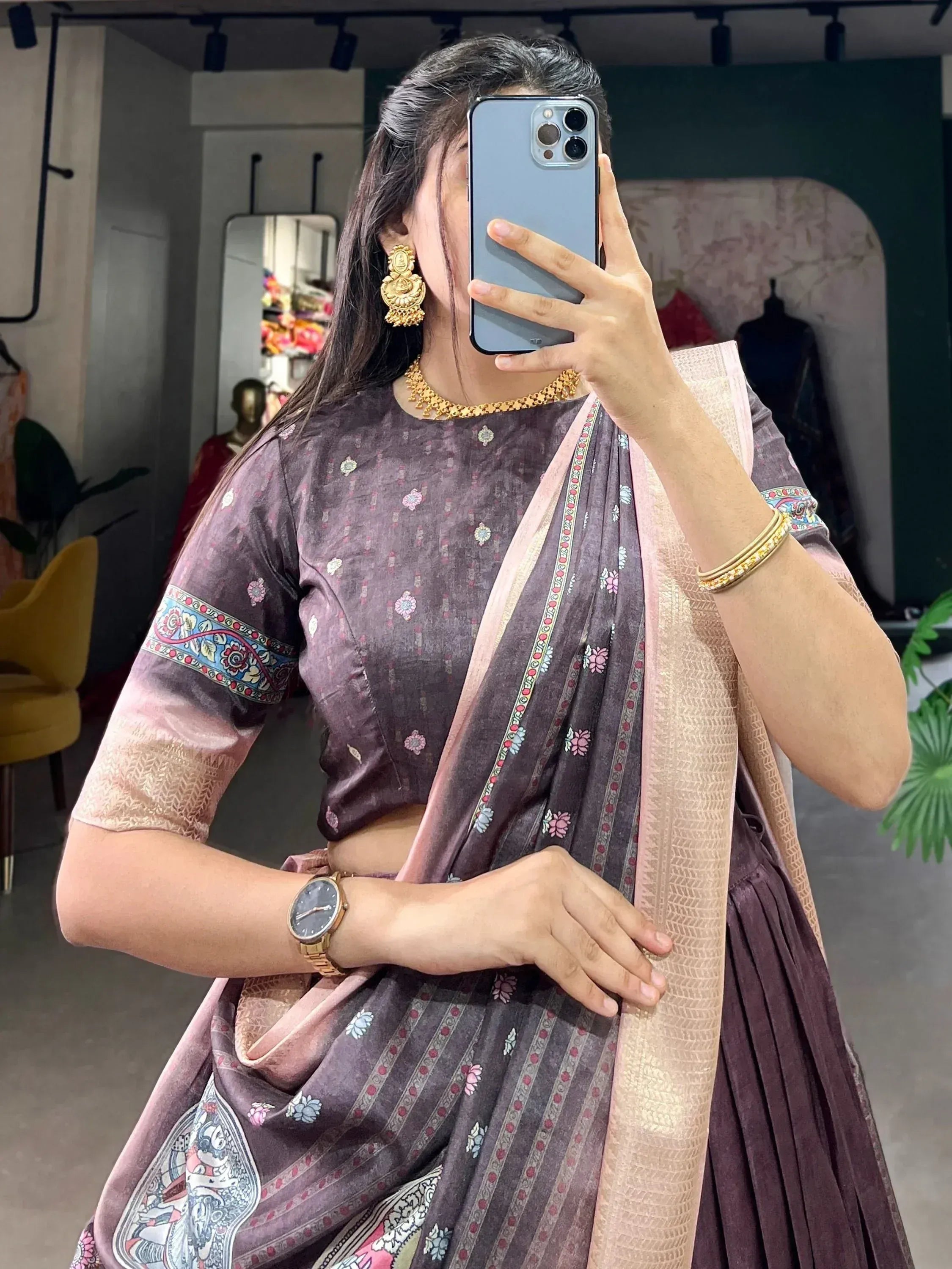 Woman in purple floral lehenga choli with pink dupatta, gold jewelry, taking mirror selfie