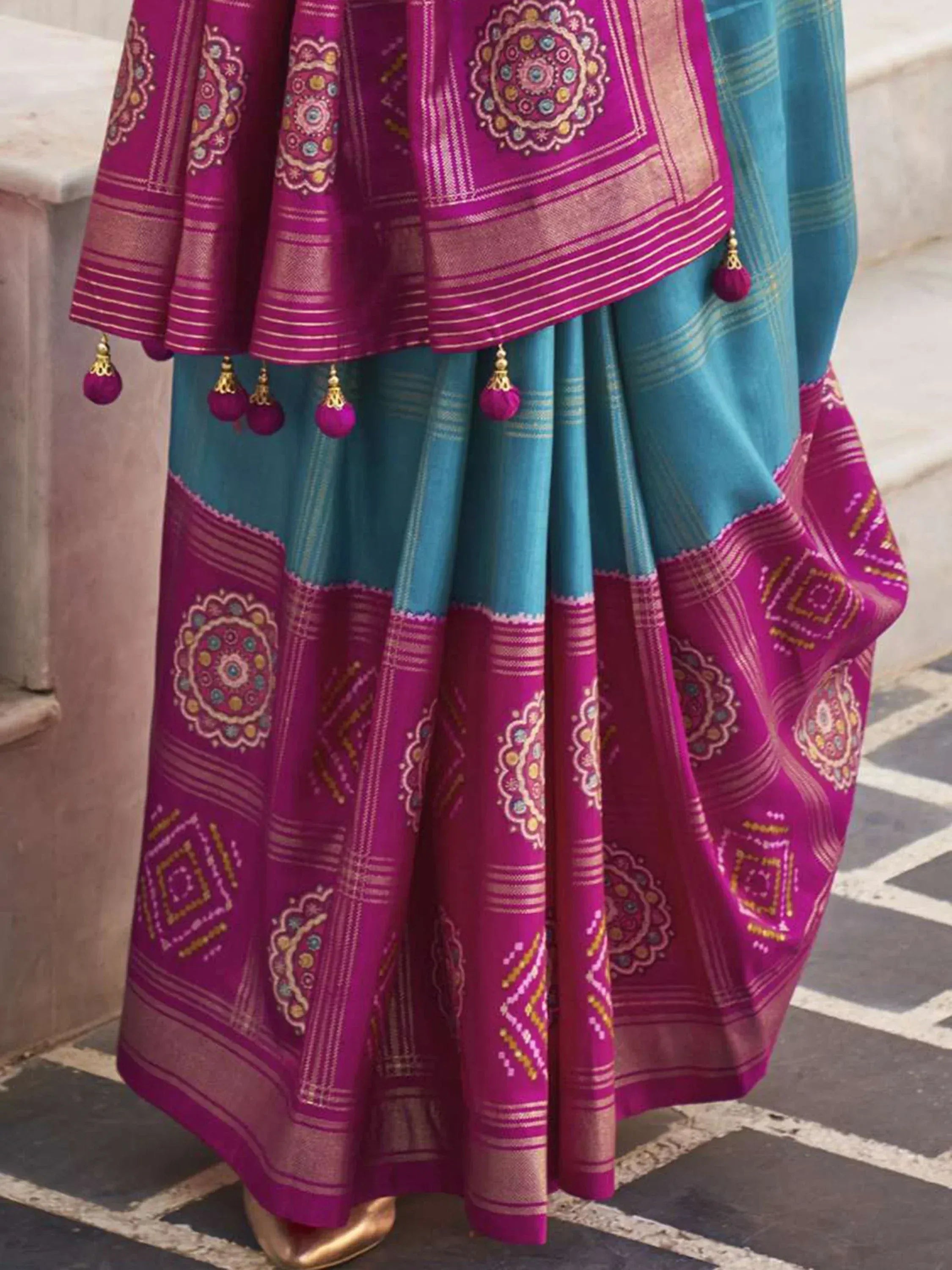 Vibrant magenta and teal Indian saree with intricate embroidery, tassels, and traditional motifs for ethnic wear.