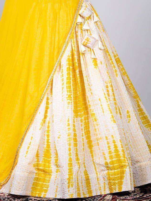 Yellow and white tie-dye lehenga choli with ruffled detailing and gold trim
