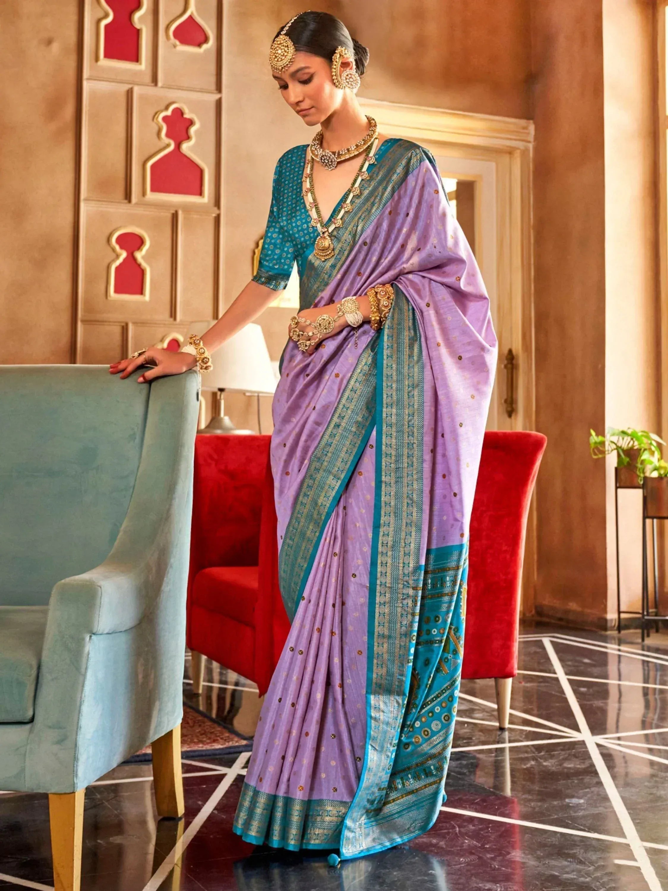 Woman in lavender and teal designer saree with gold jewelry, ethnic wear for festive occasions