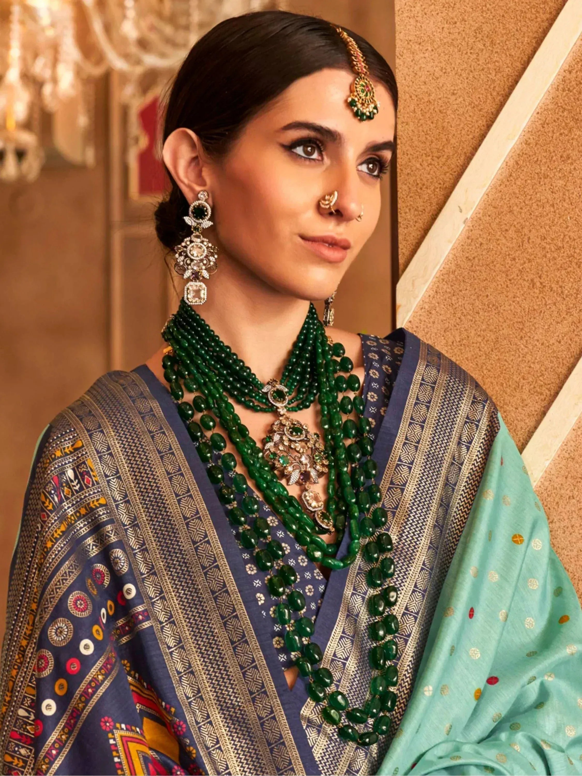 Woman in Indian ethnic wear with green beaded necklace, maang tikka, and designer earrings