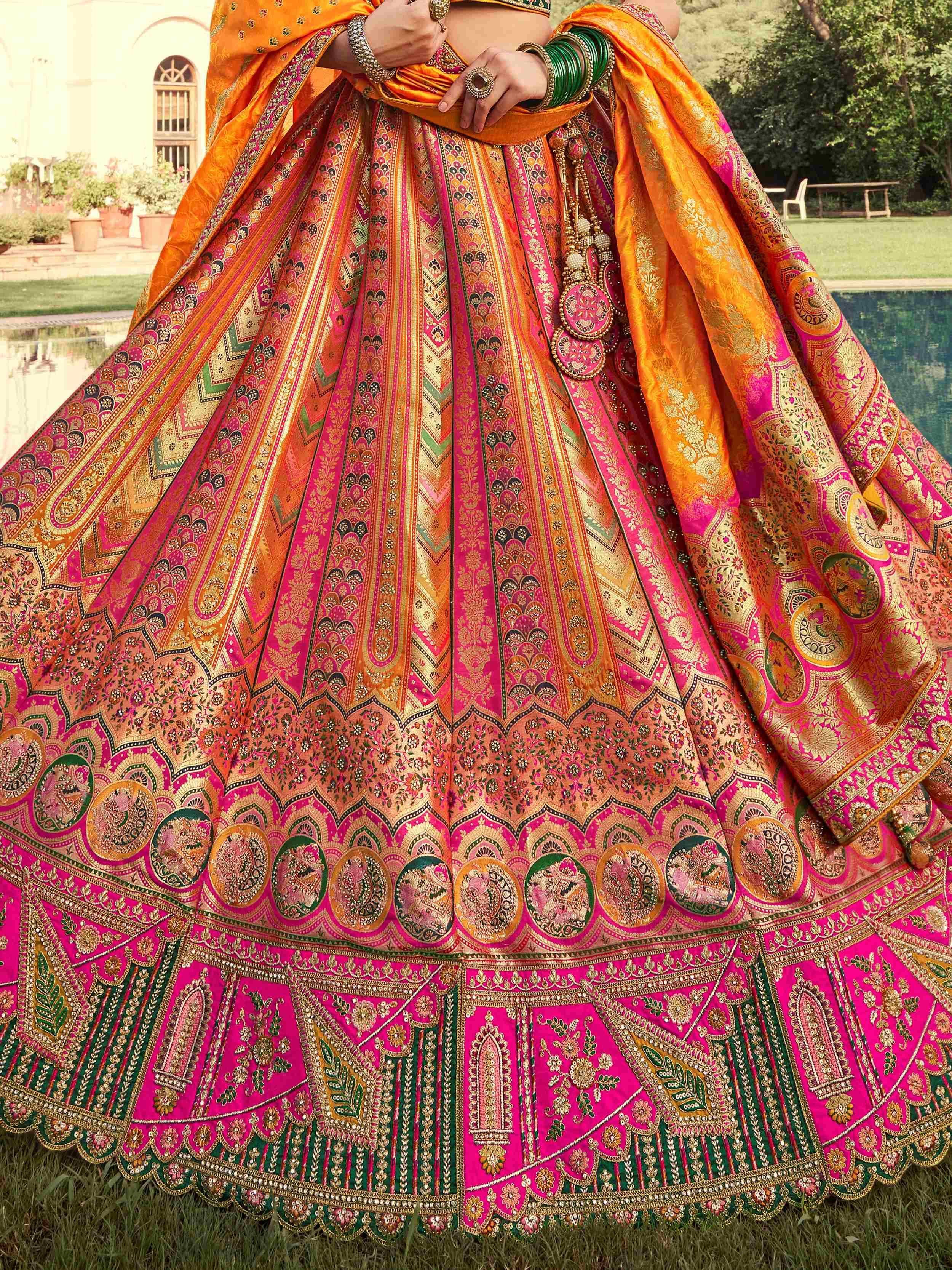 Vibrant pink and orange designer lehenga choli with intricate gold embroidery, perfect for Indian weddings and festive occasions.
