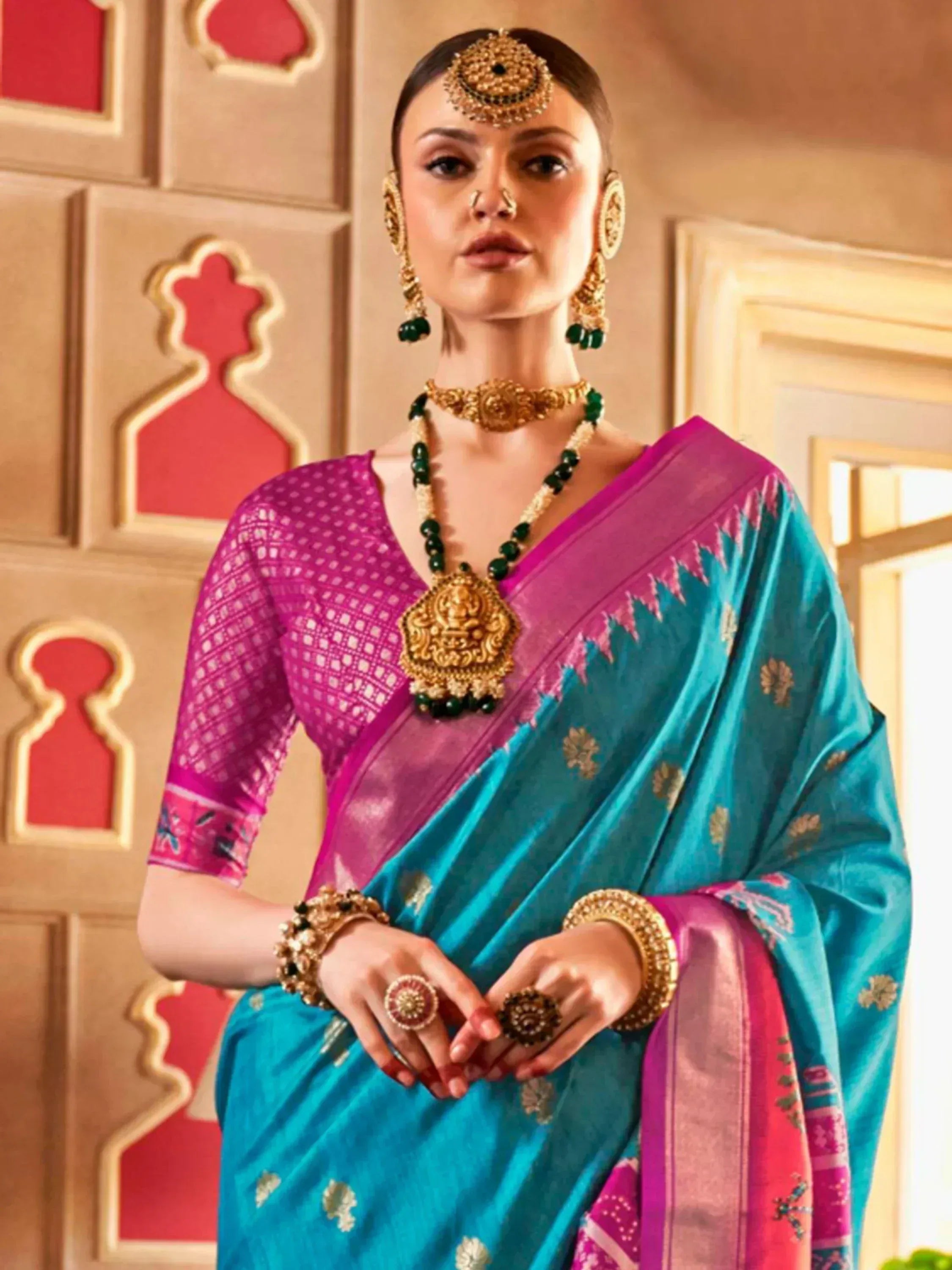 Woman in vibrant blue and pink ethnic saree with gold jewelry, traditional Indian attire