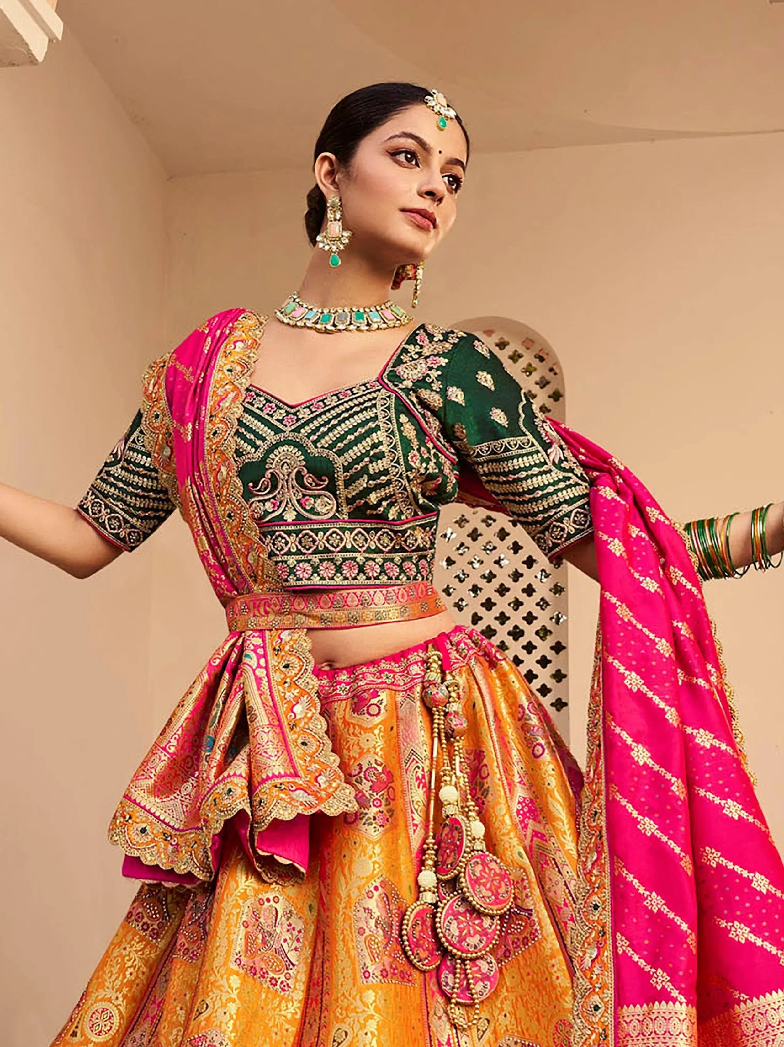 Elegant green and pink embroidered lehenga choli with heavy jewelry, perfect for Indian weddings and festivals.