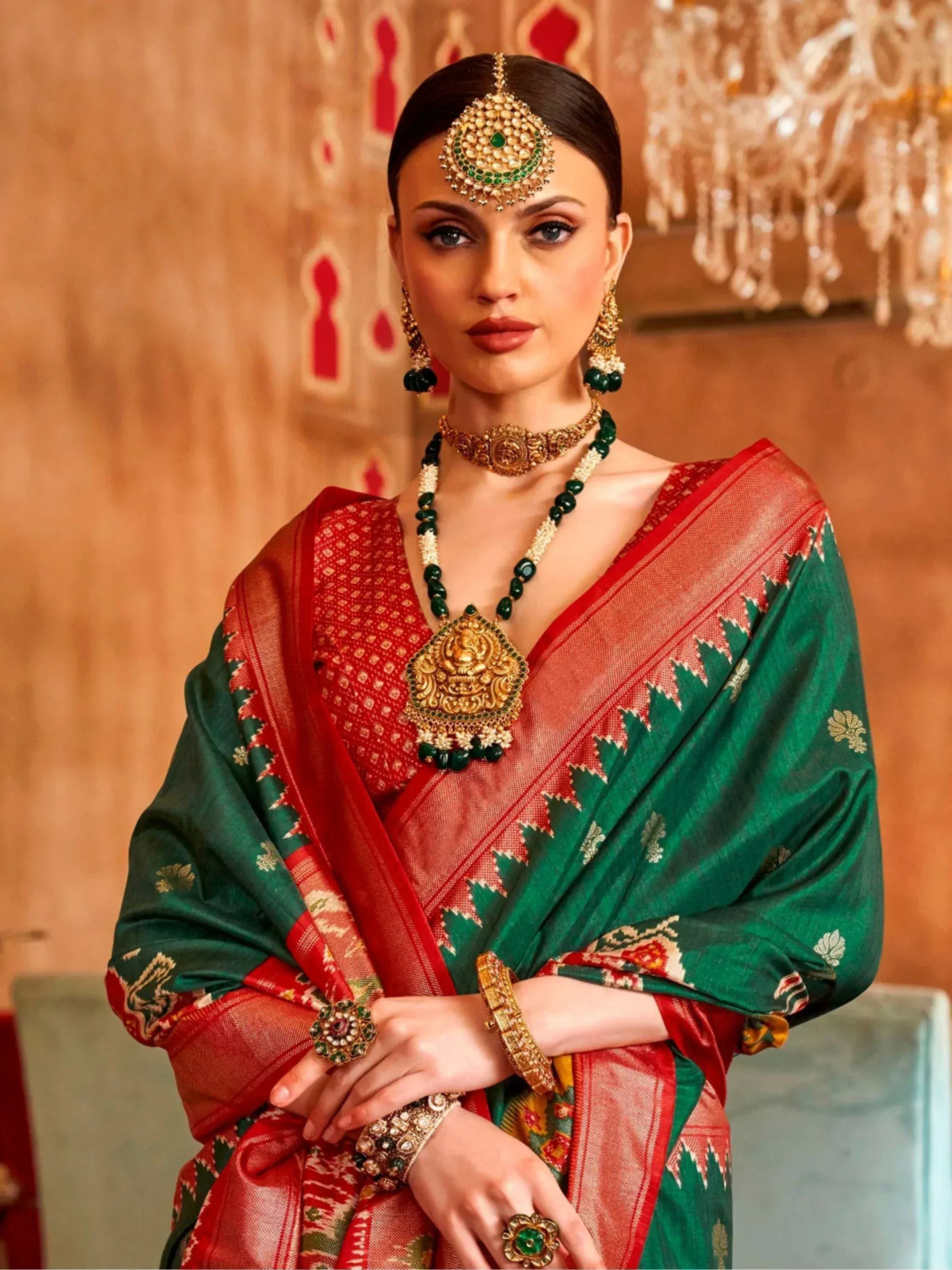 Elegant woman in red and green Indian saree with gold jewelry, perfect for ethnic occasions