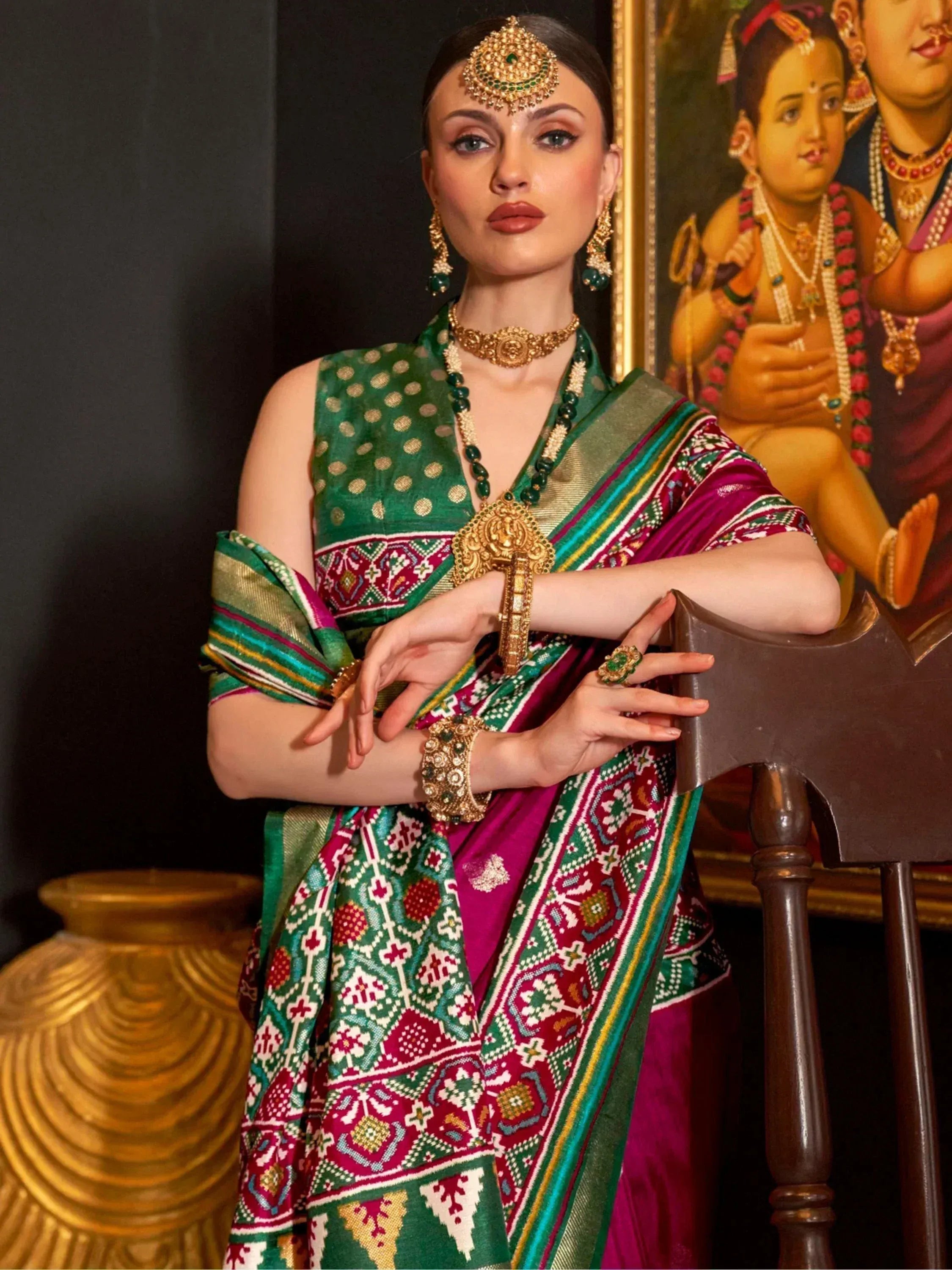 Woman in vibrant green and magenta ethnic saree with gold jewelry, traditional Indian attire