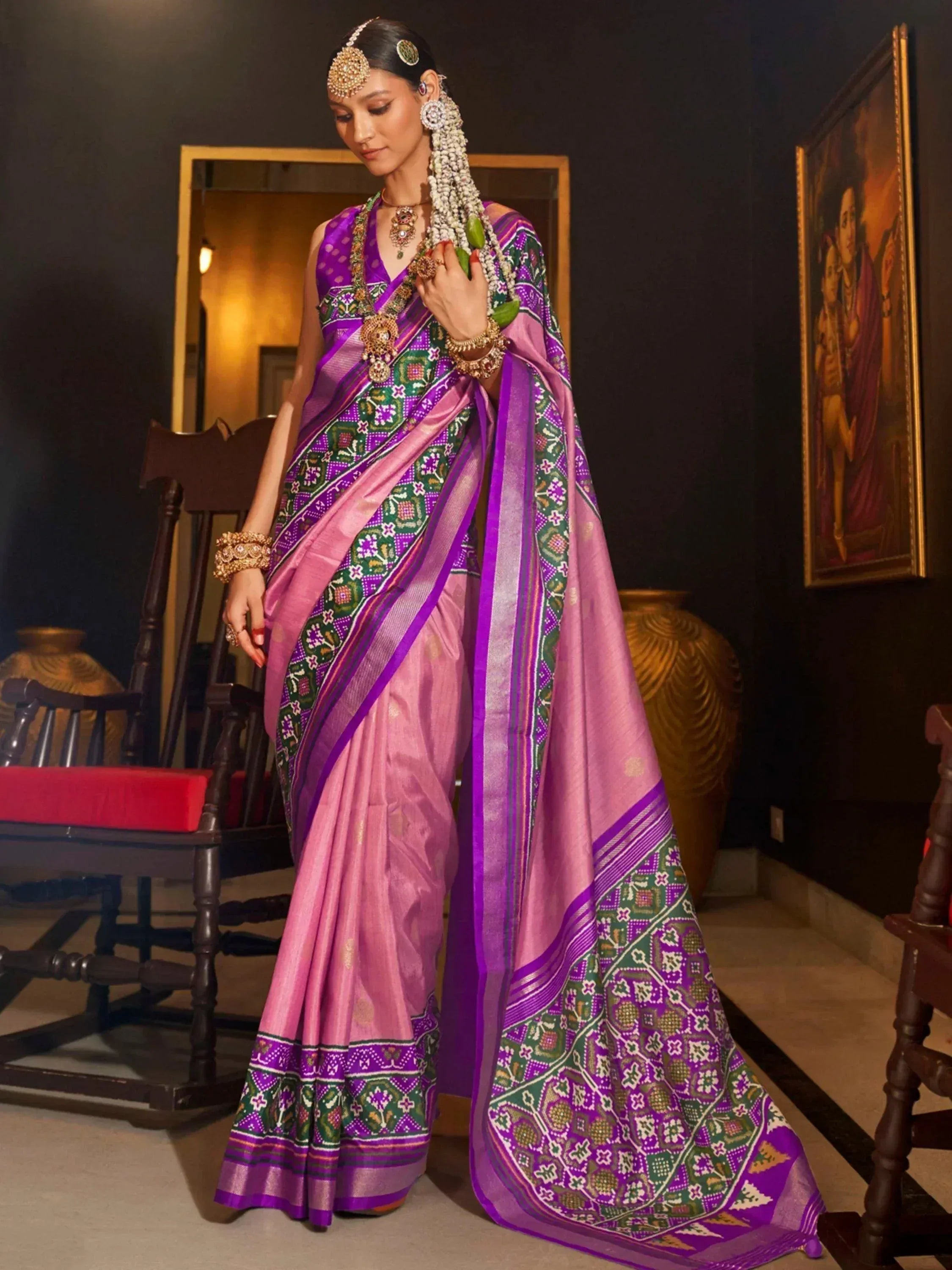 Woman in purple and pink designer saree with green floral border, traditional Indian ethnic wear