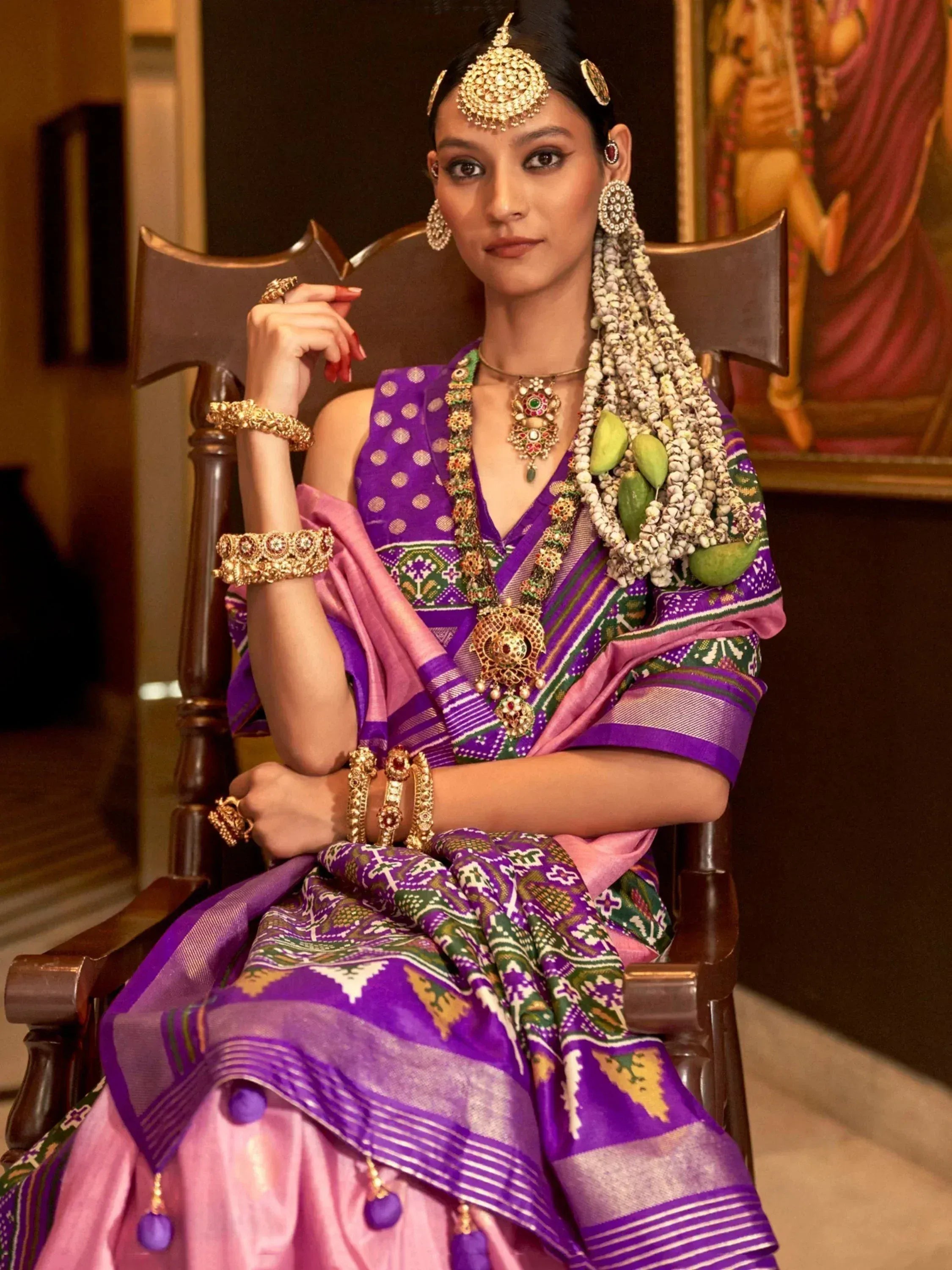 Woman in purple and pink ethnic saree with gold jewelry, traditional Indian attire for festive occasions