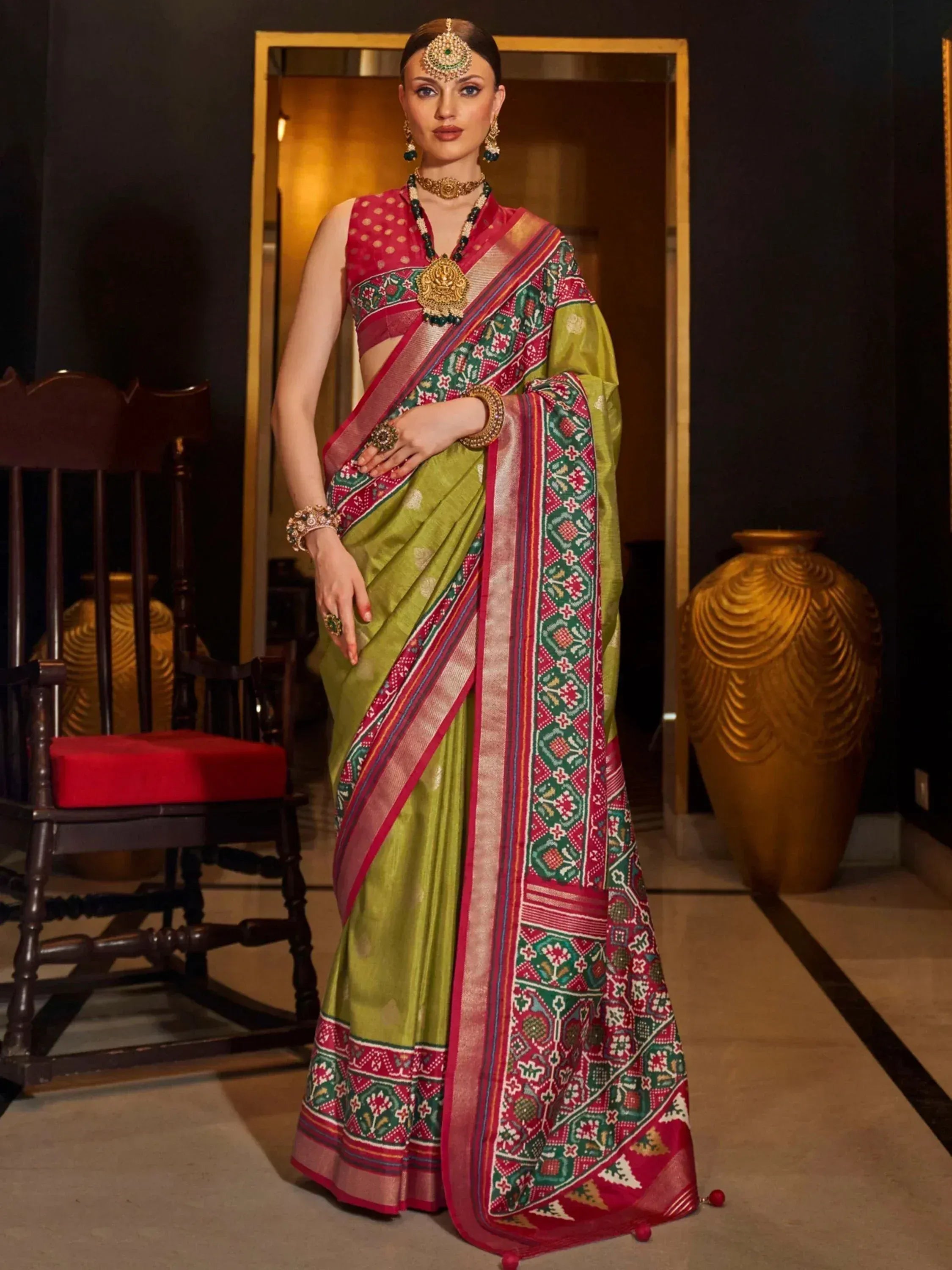 Green and red printed ethnic saree with gold jewelry, perfect for Indian occasions and festivals.